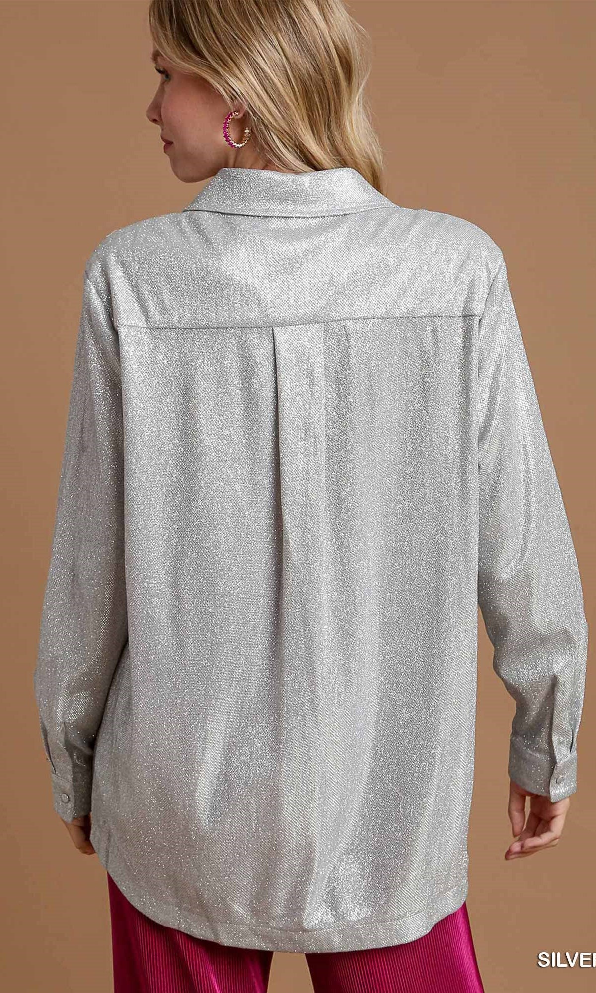 Woman wearing a silver metallic shirt against a brown background