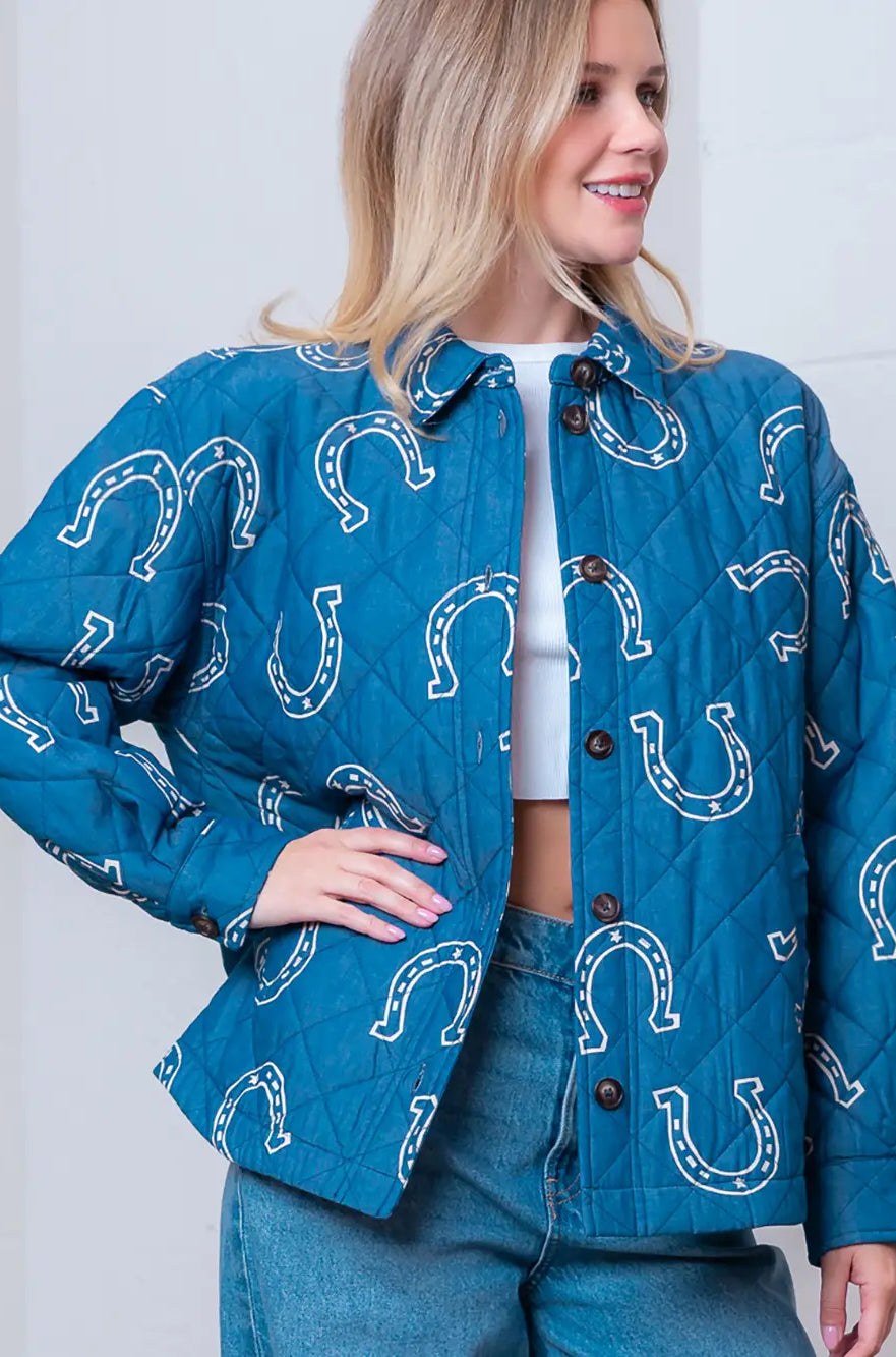 Front view of denim-blue quilted jacket with white horseshoe print and button front on model.