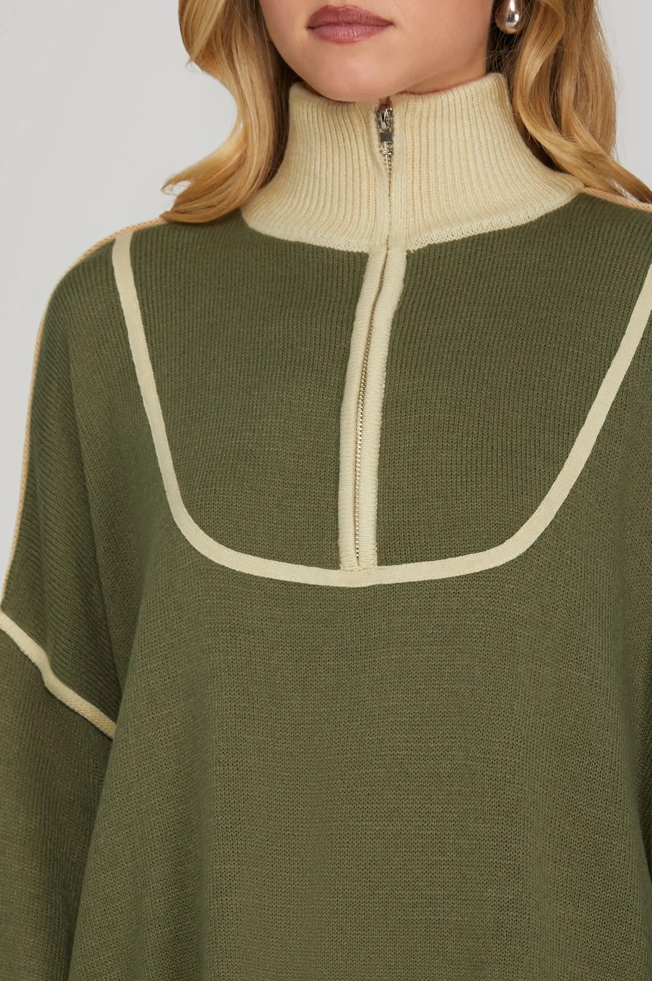 Green sweater with cream trim on a plain background