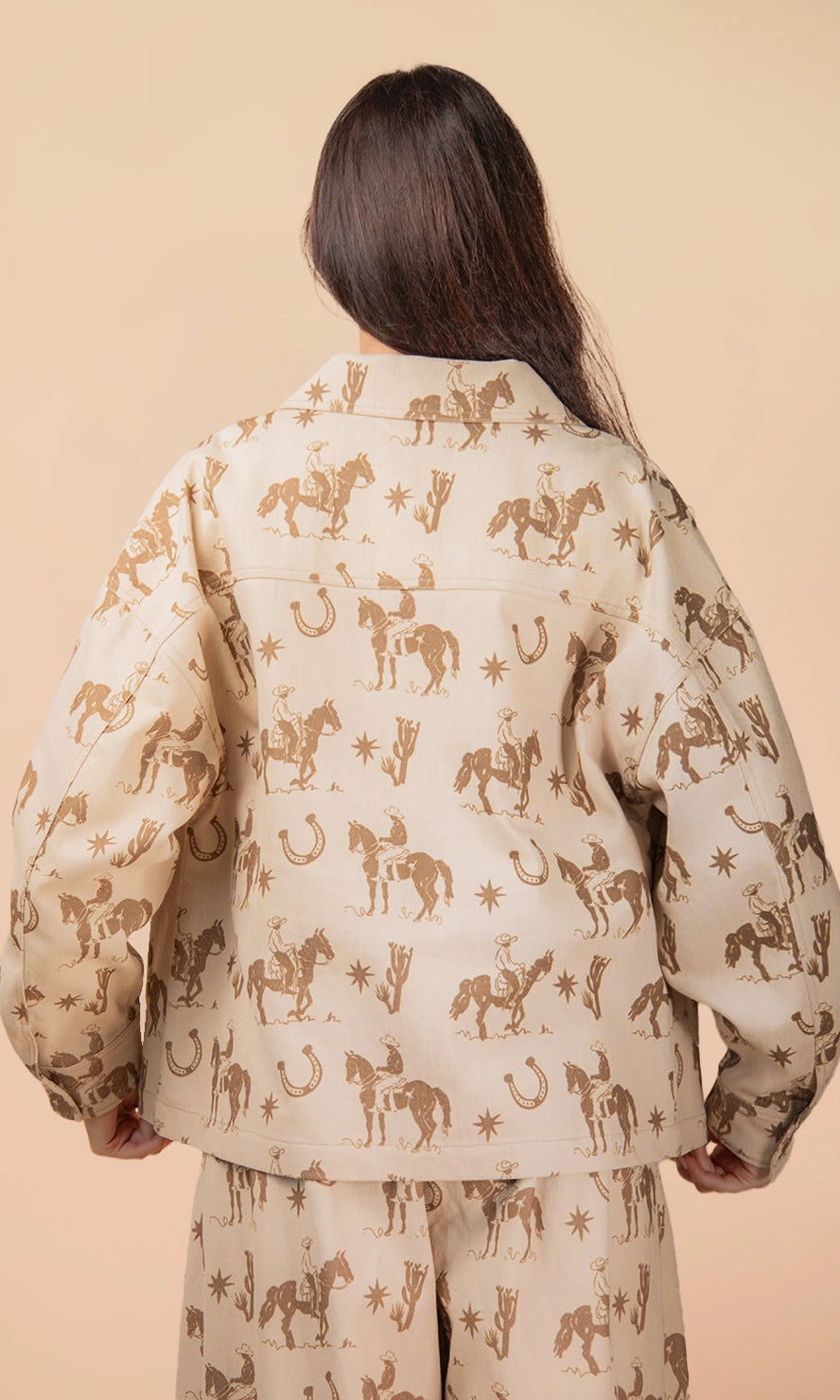 Person wearing a beige shirt with horse pattern on a beige background