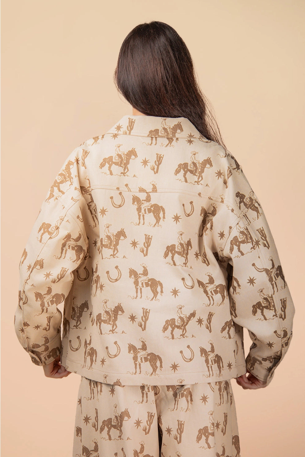 Person wearing a beige shirt with horse pattern on a beige background