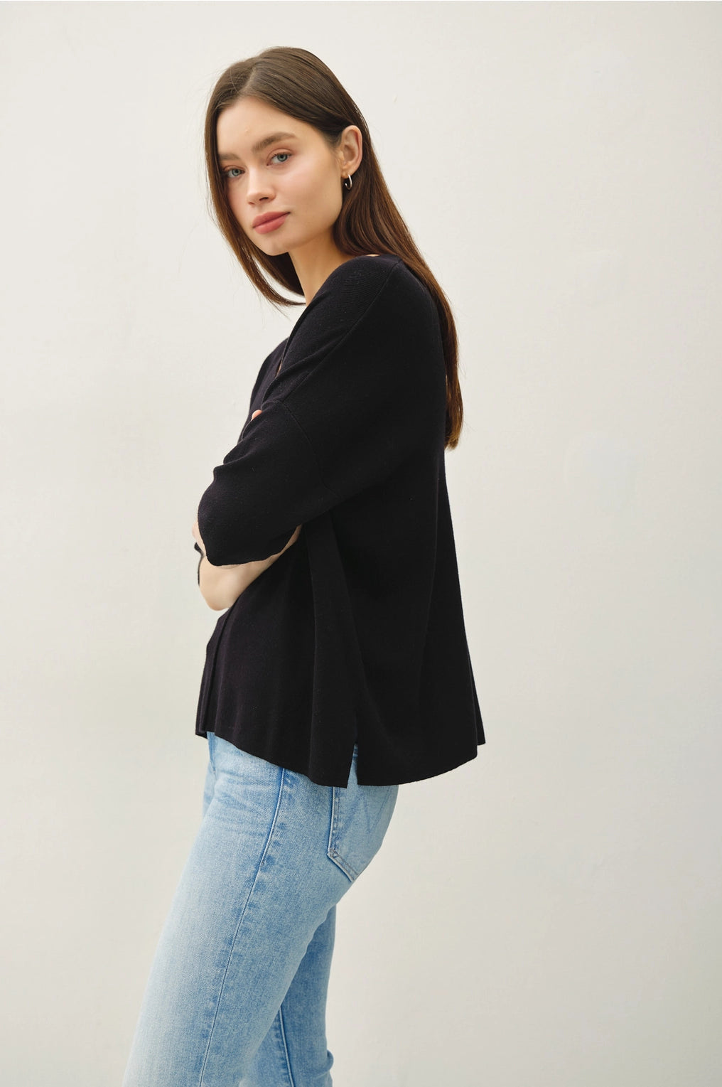 Woman wearing a black top and light blue jeans against a white background