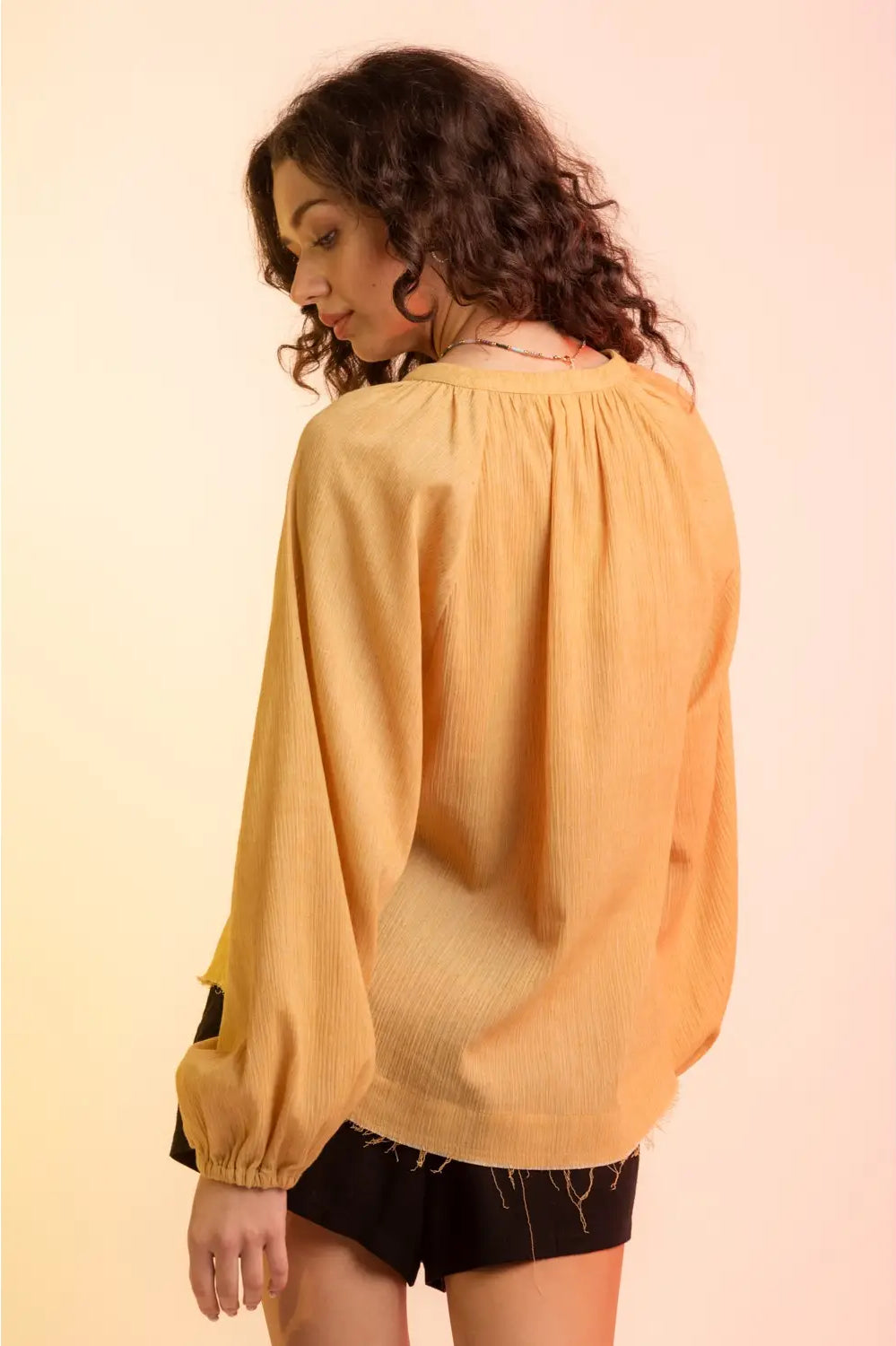 Back view: Back of yellow gauze blouse showing gathered neckline and elastic cuffs.