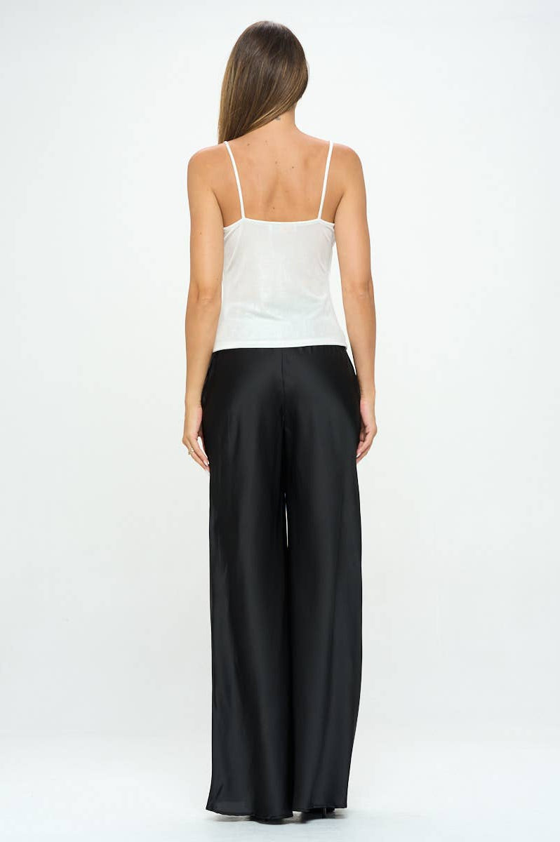 Woman wearing a white top and black pants on a white background