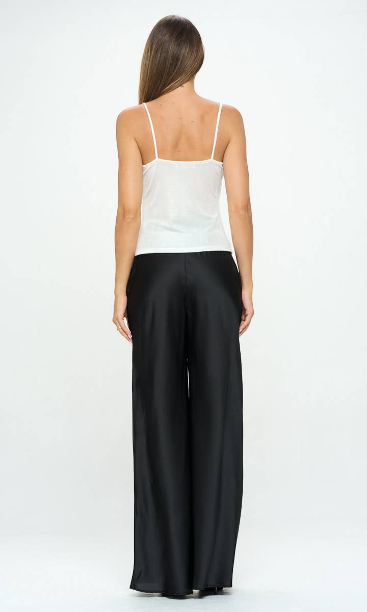 Woman wearing a white top and black pants on a white background