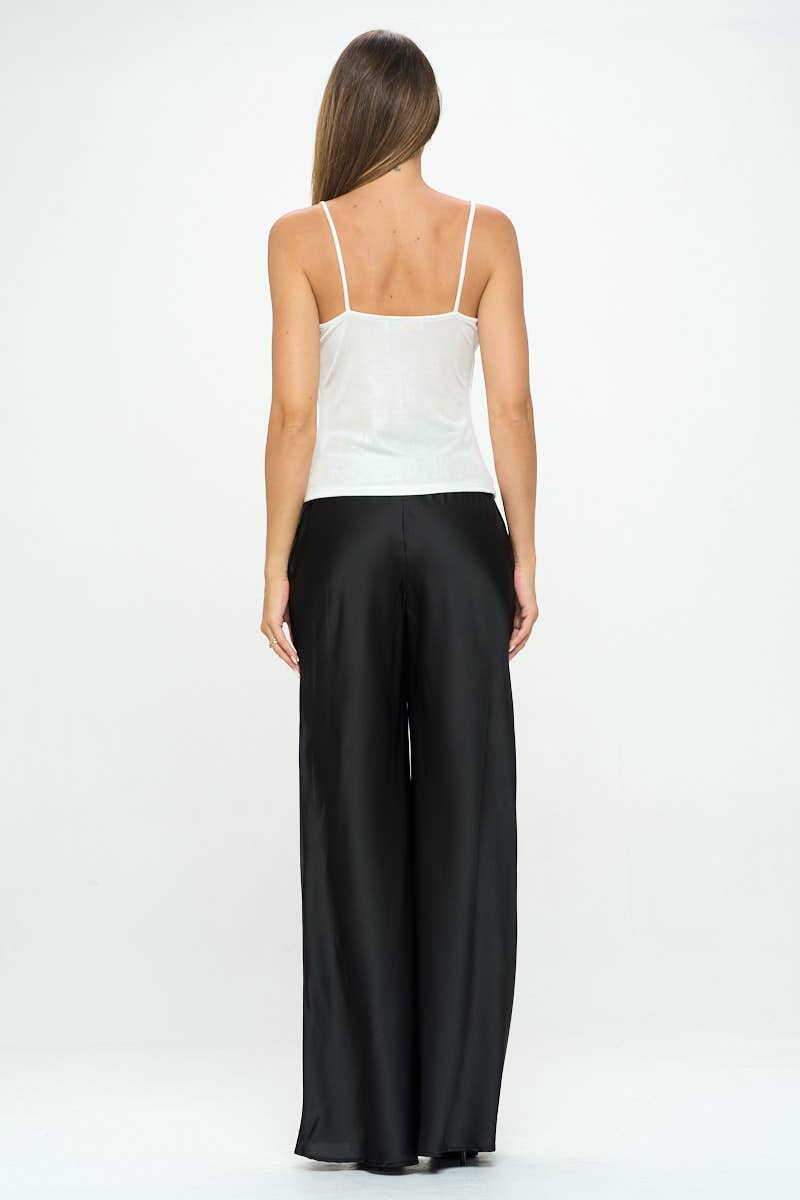 Woman wearing a white top and black pants on a white background