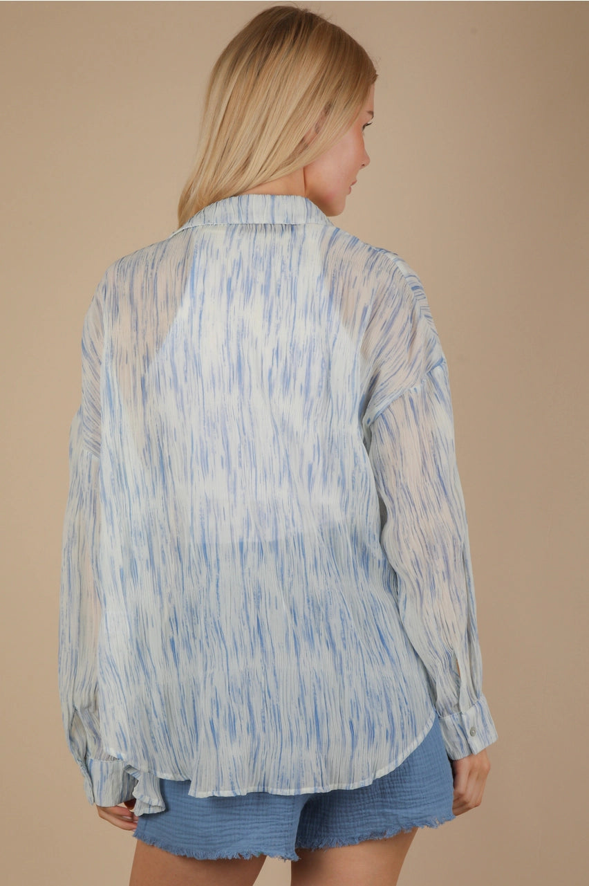 Back view of the sky-blue brushstroke pleated button-down, highlighting the hi-lo curved hem and semi-sheer crinkle fabric.