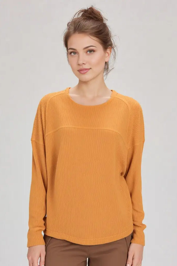 Woman wearing a mustard yellow sweater against a plain background