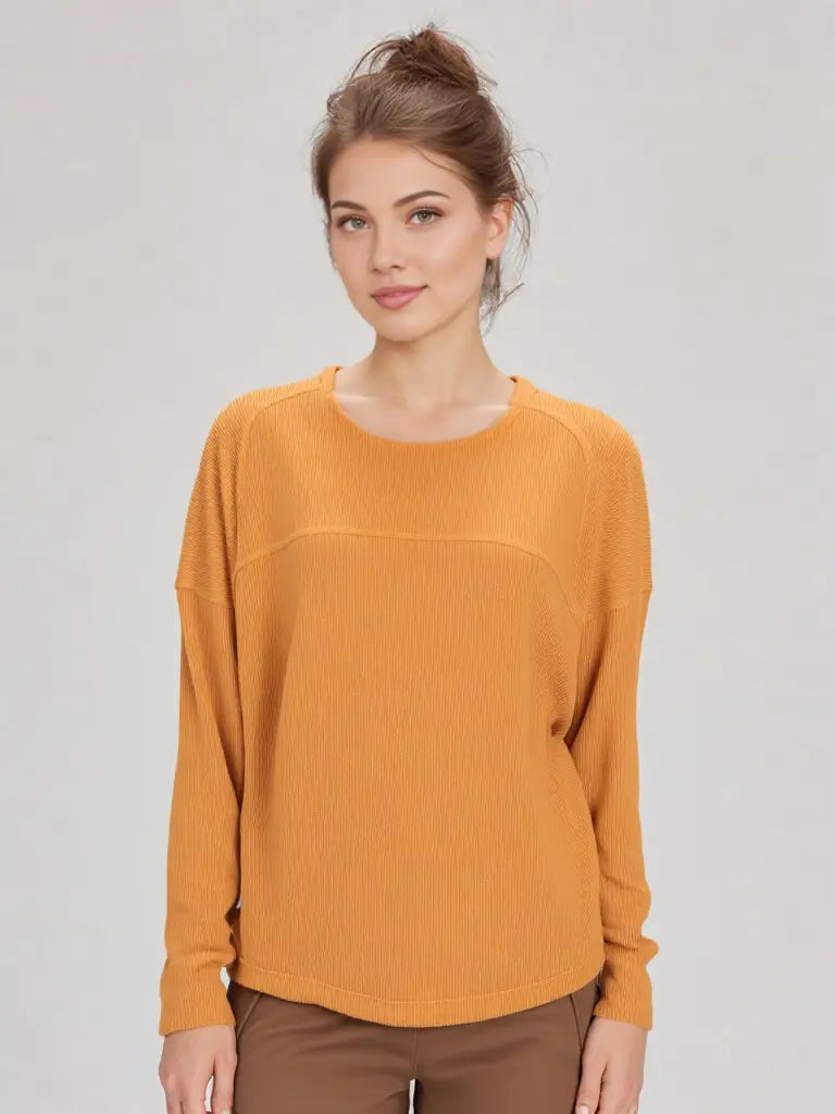 Woman wearing a mustard yellow sweater against a plain background