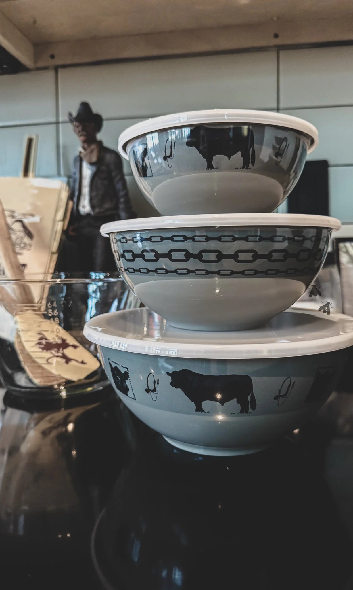 Stack of melamine bowls with black angus cow illustrations on a reflective surface