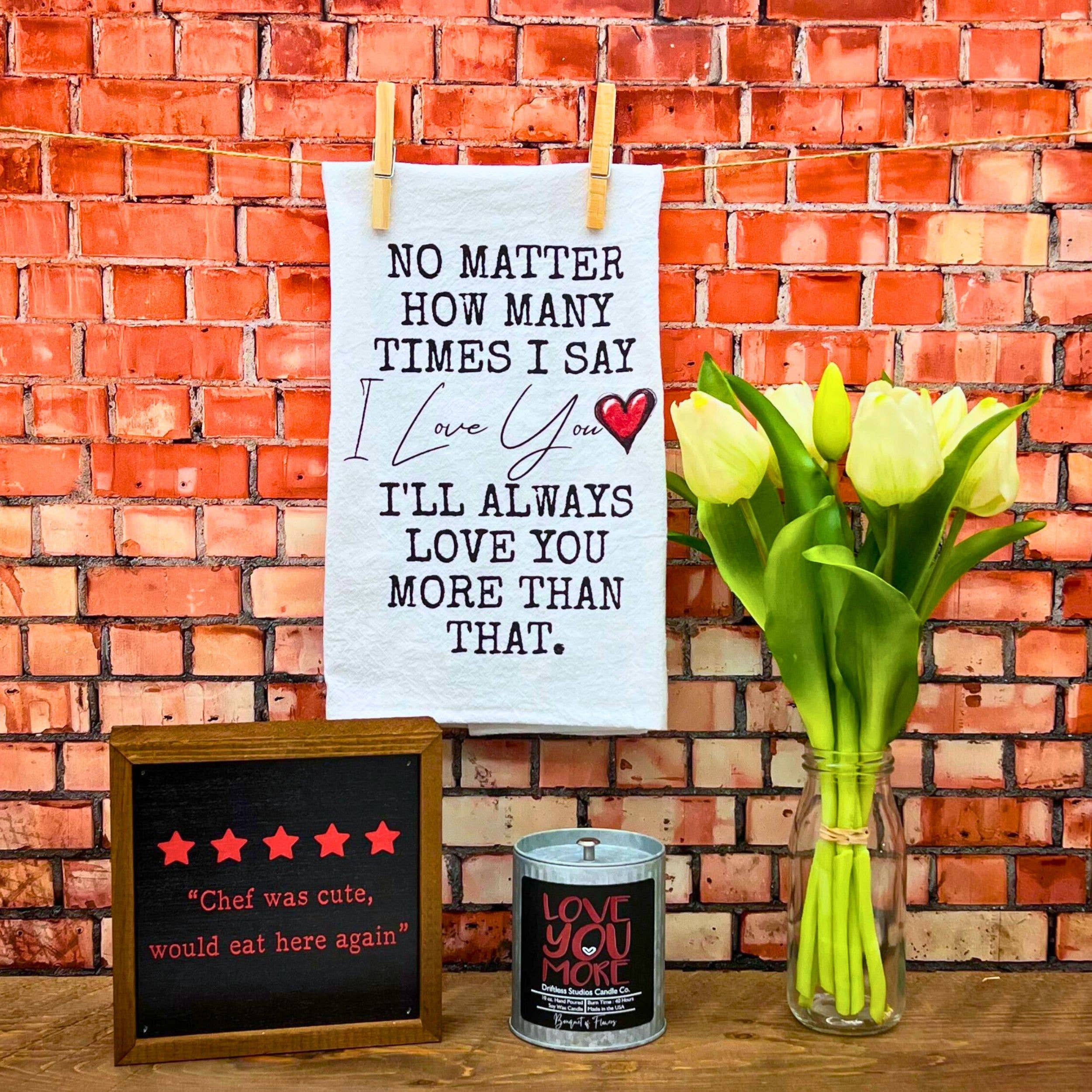 Decorative setup with a sign, tulips, and a small board against a brick wall.