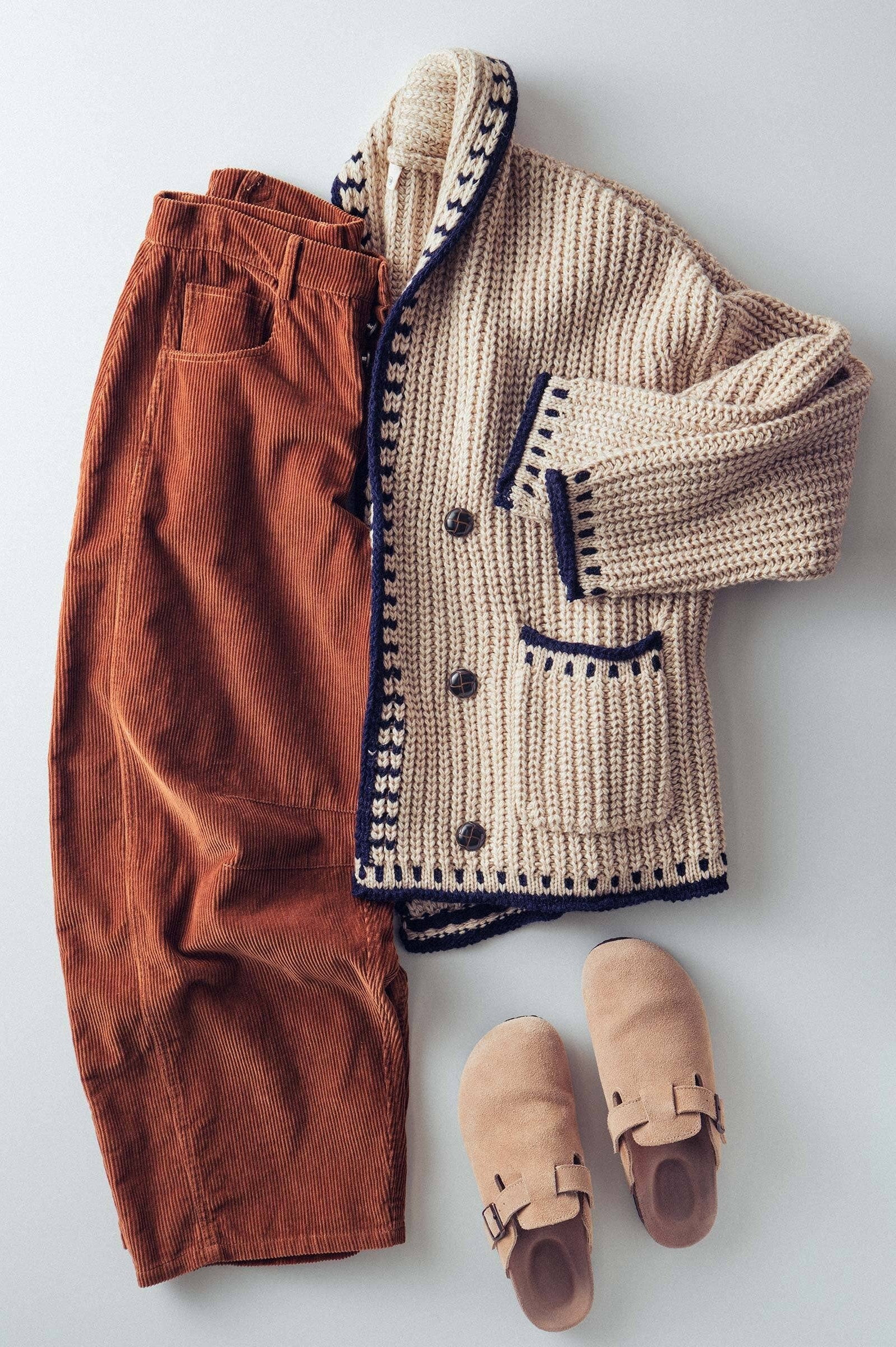 Knitted beige cardigan, brown pants, and tan shoes on a light gray background