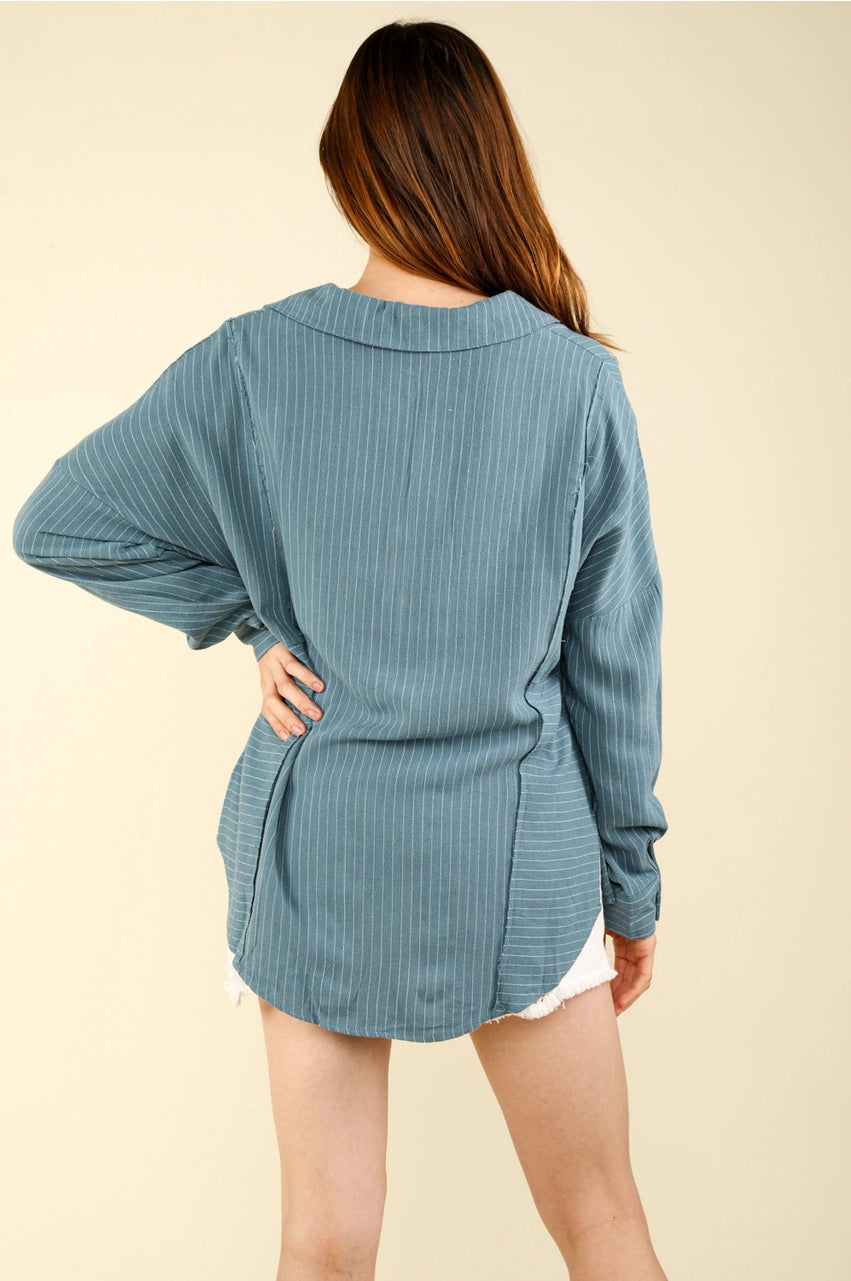 Back view of dusty-blue striped oversized collared shirt showing curved hem and relaxed fit on model.”