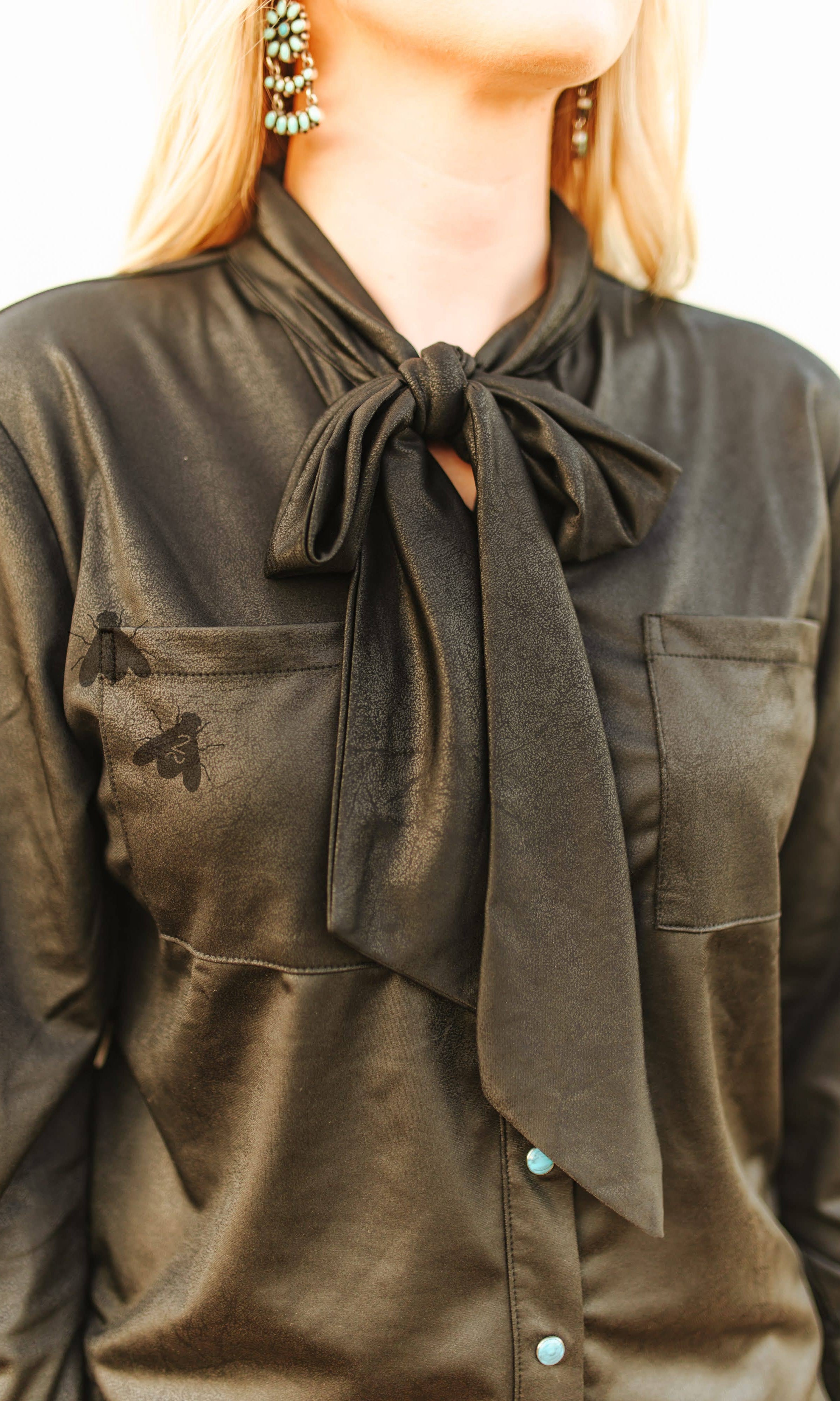 Black faux leather shirt with a bow tie worn by a person