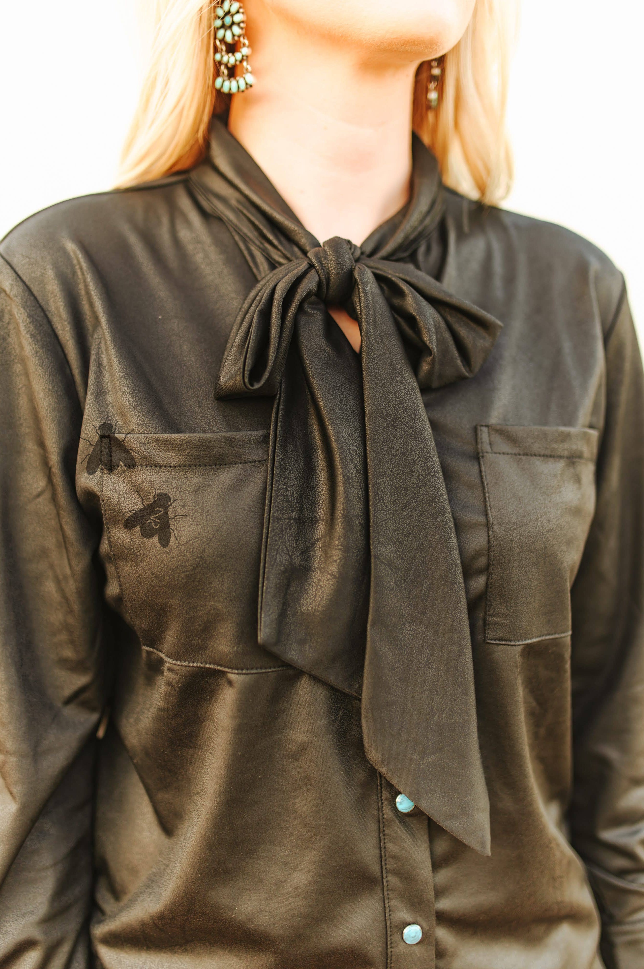 Black faux leather shirt with a bow tie worn by a person