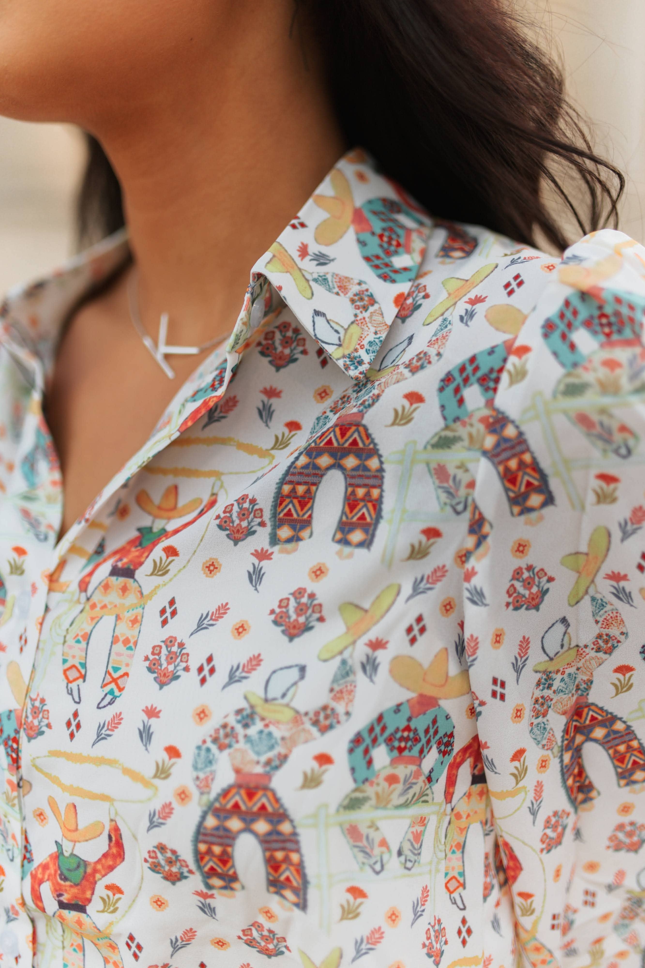 Close-up of a person wearing a colorful patterned shirt with elephants and other designs.