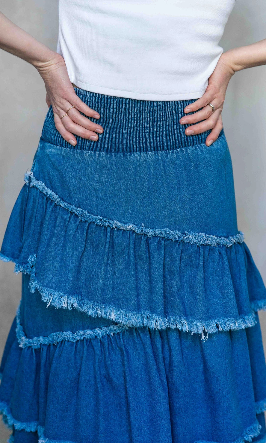 Blue tiered skirt worn by a person against a neutral background