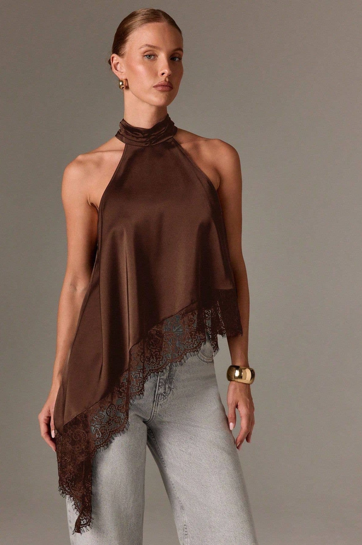 Woman wearing a brown halter top with lace details on a plain background