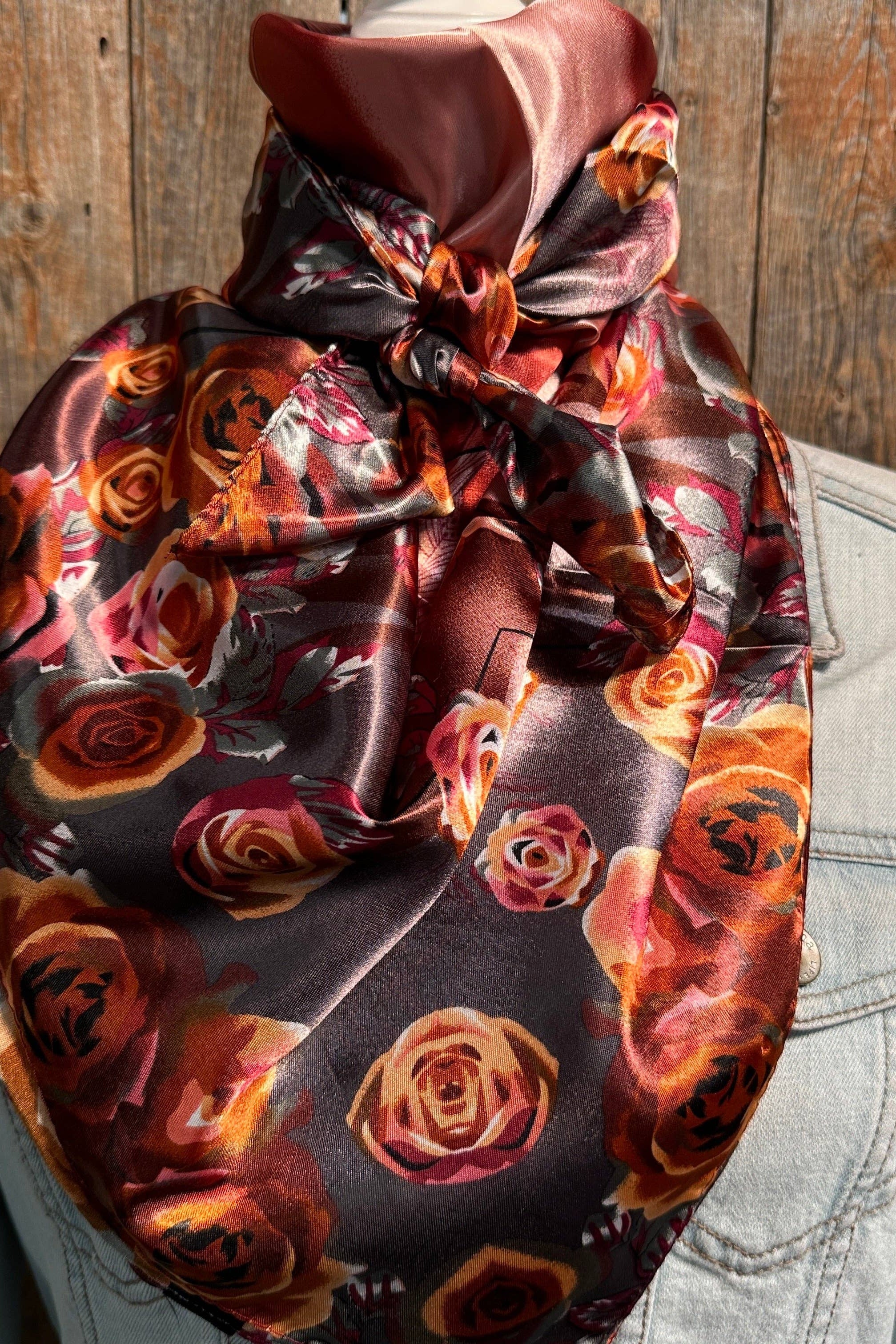 Scarf with floral pattern draped over a light-colored jacket against a wooden background
