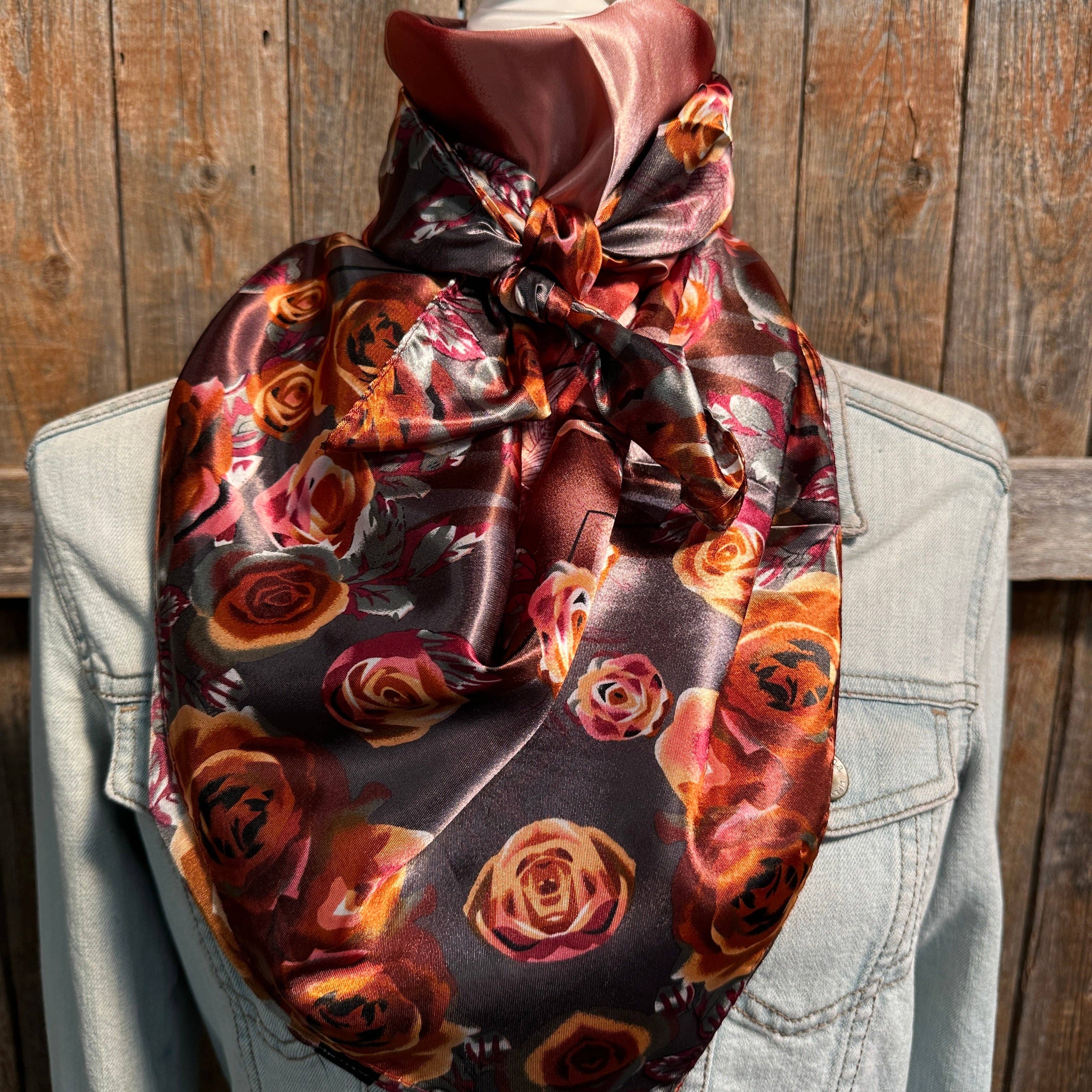 Scarf with floral pattern draped over a light-colored jacket against a wooden background