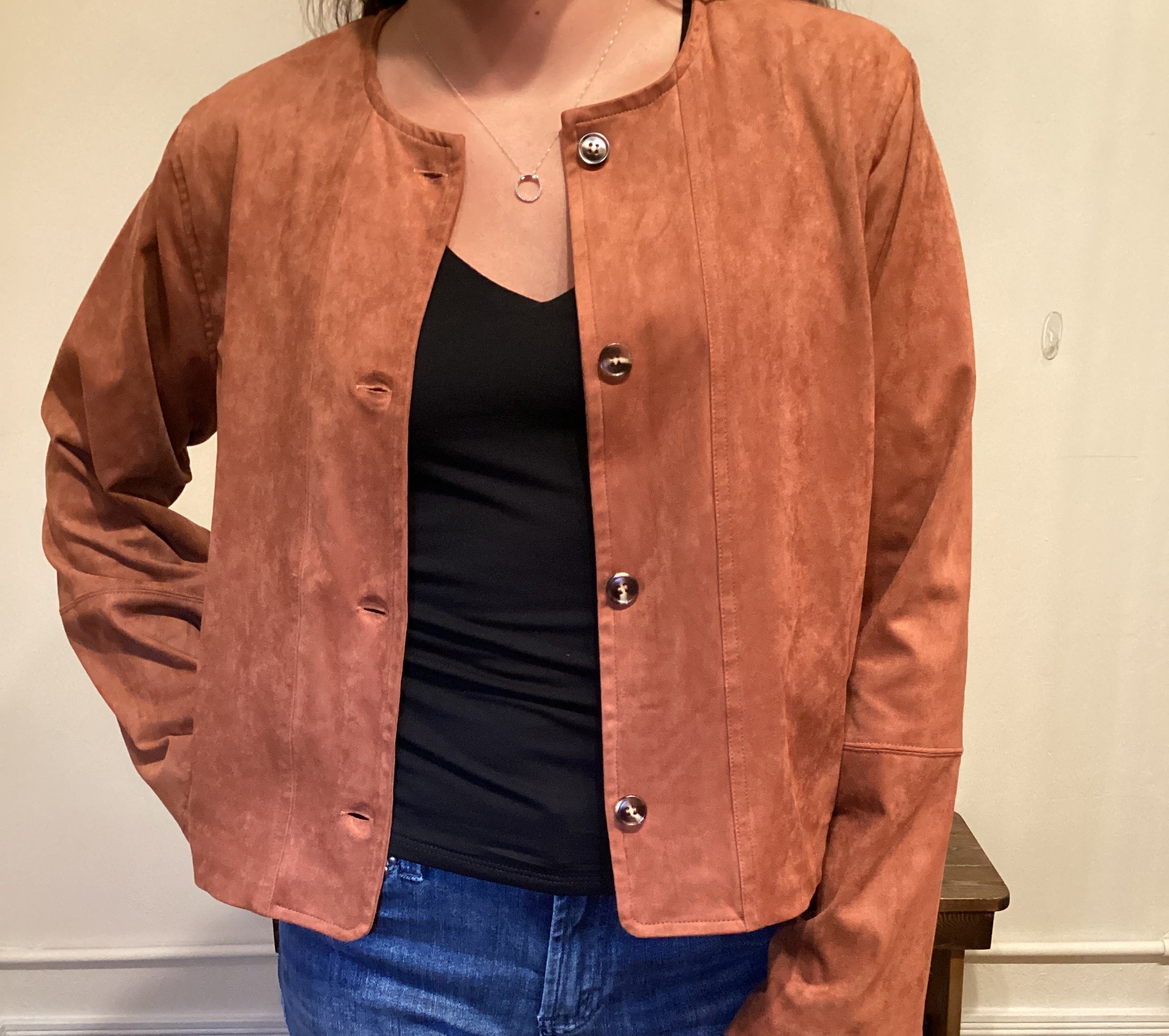 Person wearing a brown faux leather button up jacket and blue jeans