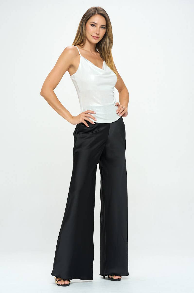 Woman wearing a white top and black wide-leg pants on a white background