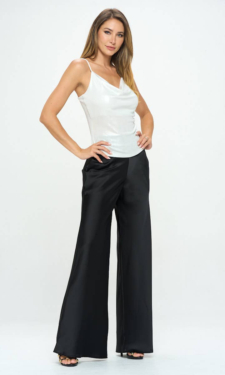 Woman wearing a white top and black wide-leg pants on a white background