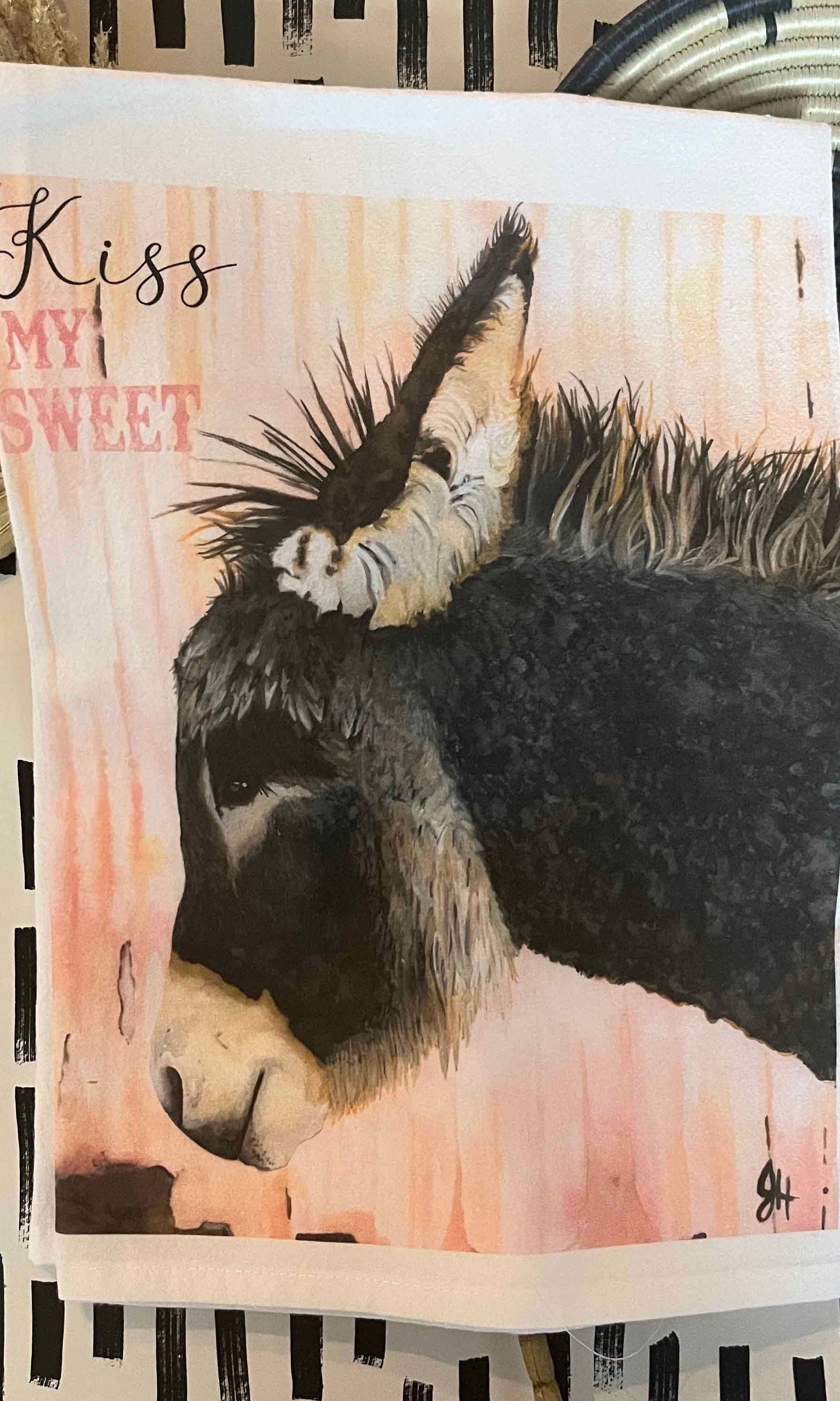 Tea towel with a donkey illustration and 'Kiss My Sweet' text on a patterned background