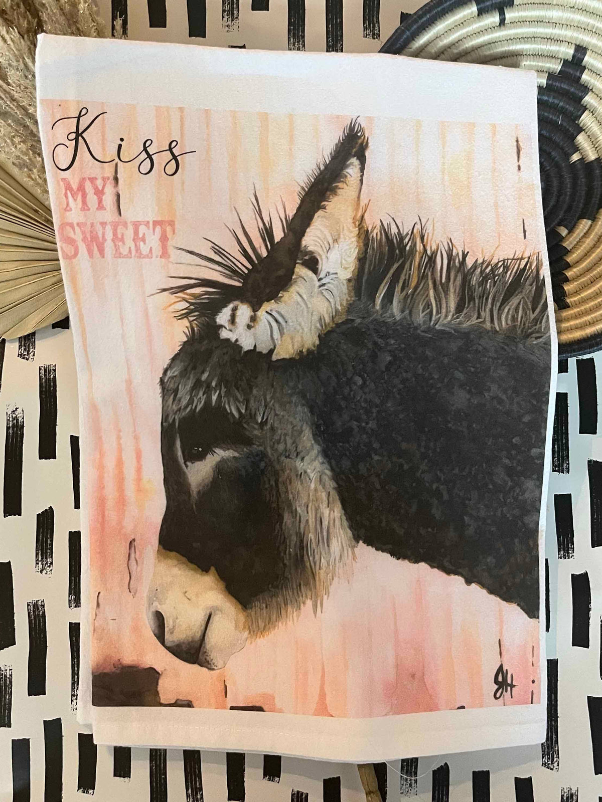 Tea towel with a donkey illustration and 'Kiss My Sweet' text on a patterned background