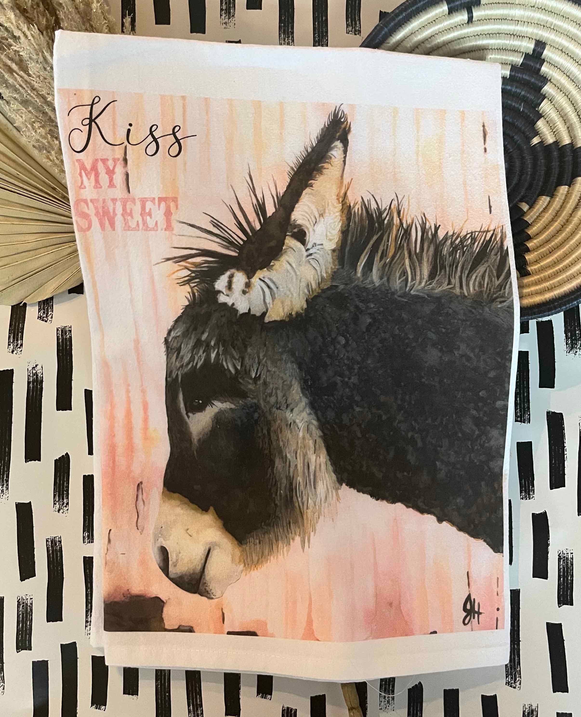 Tea towel with a donkey illustration and 'Kiss My Sweet' text on a patterned background