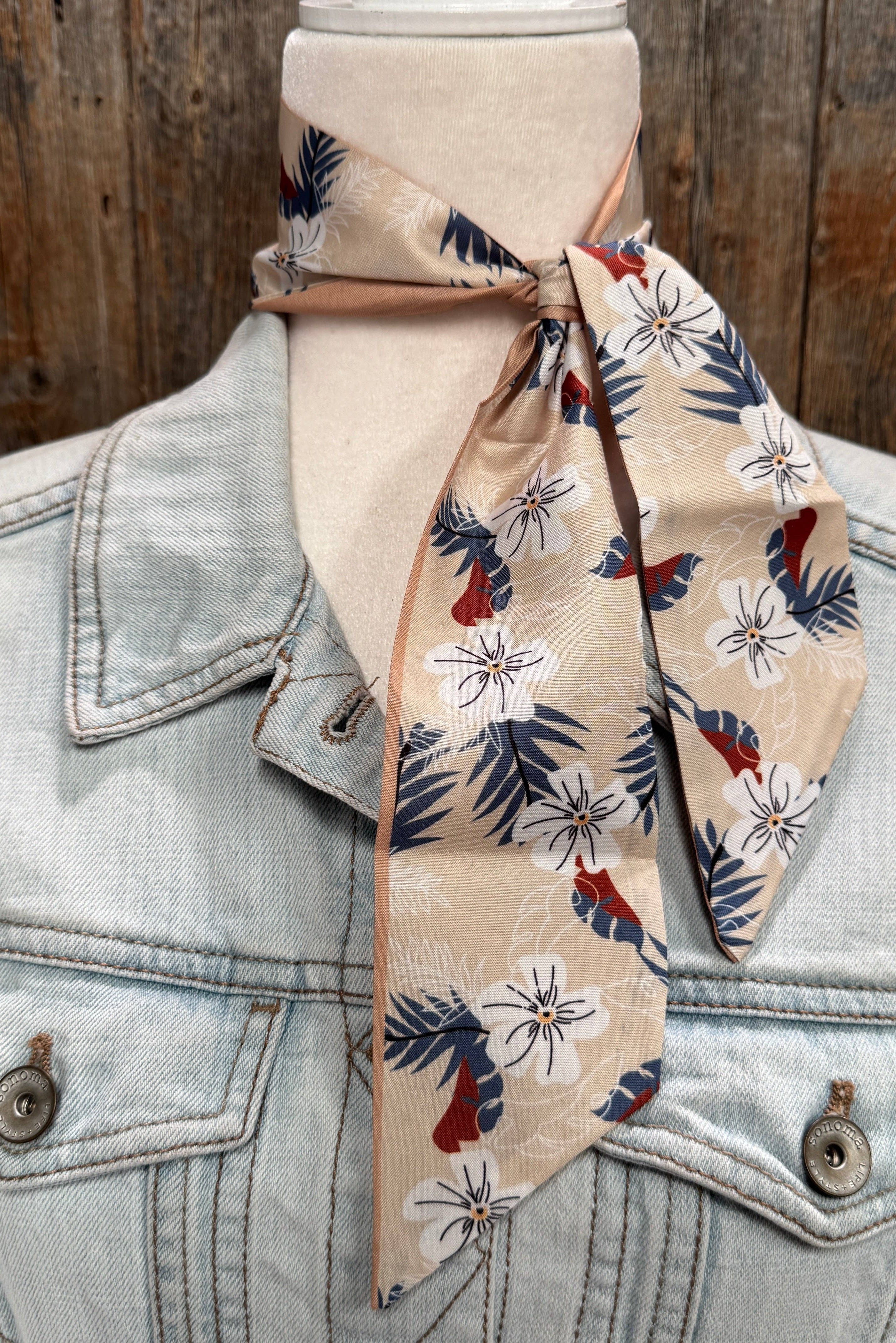 Denim jacket with a floral patterned scarf draped over it against a wooden background