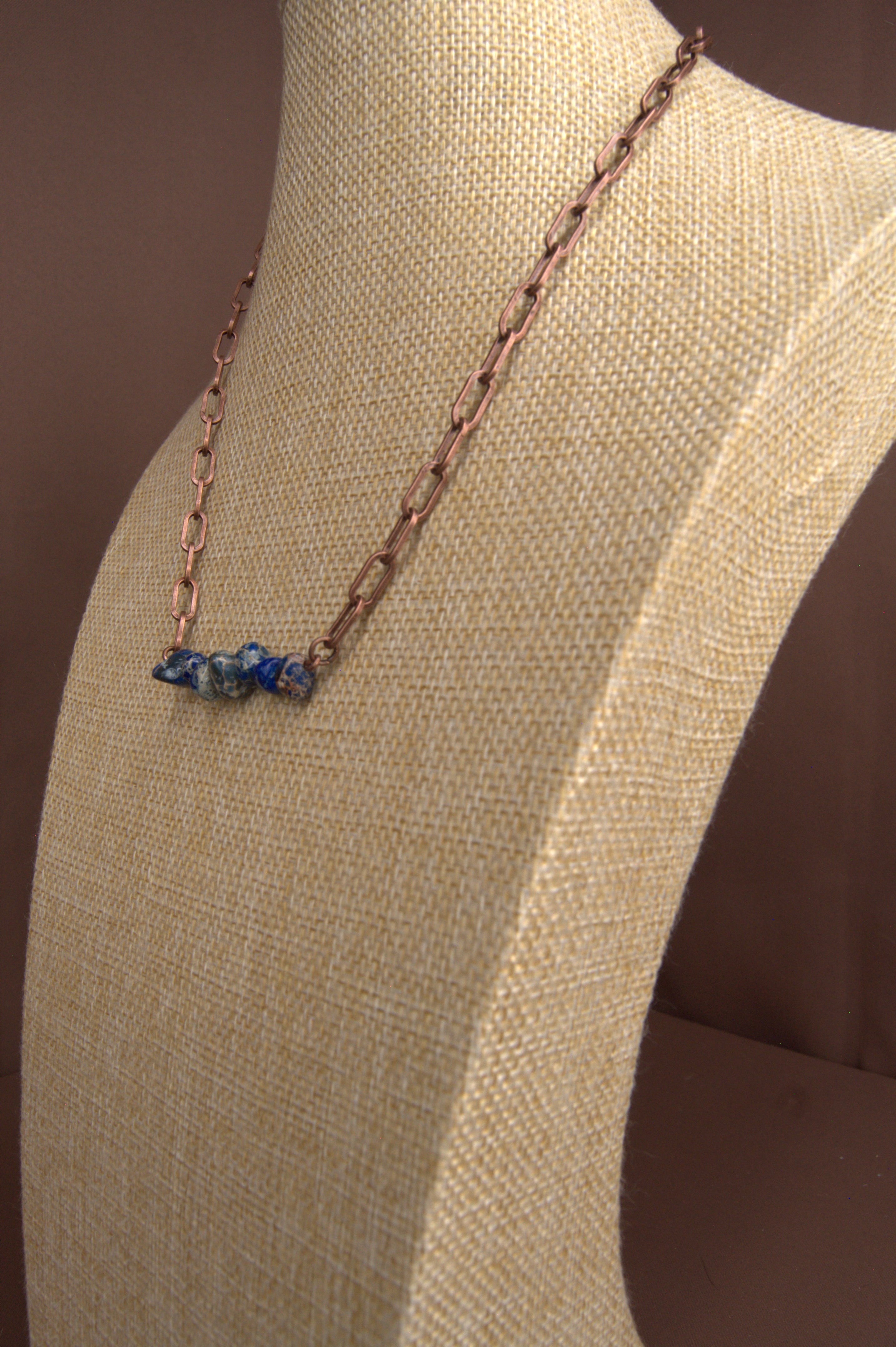 Close-up of a necklace with blue stones on a beige fabric background