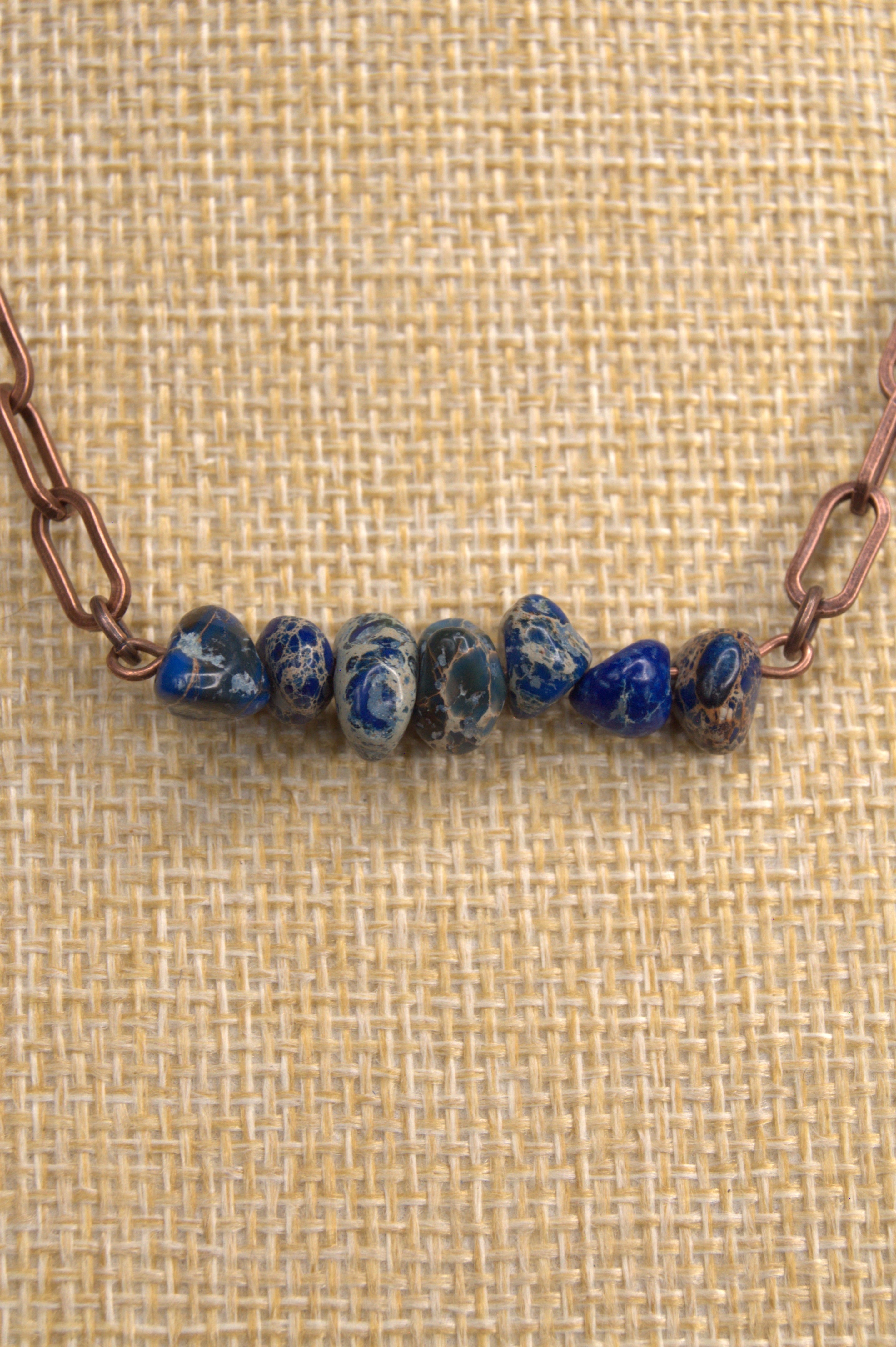 Beaded keychain with blue beads on a textured beige background