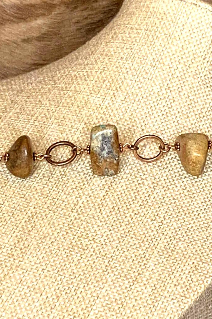 Detailed view of rustic stone bracelet with copper chain links and polished earth-tone stones in rectangular and rounded shapes.