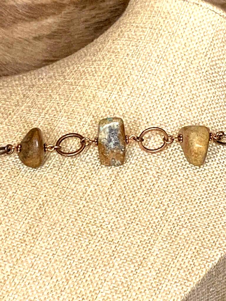 Detailed view of rustic stone bracelet with copper chain links and polished earth-tone stones in rectangular and rounded shapes.