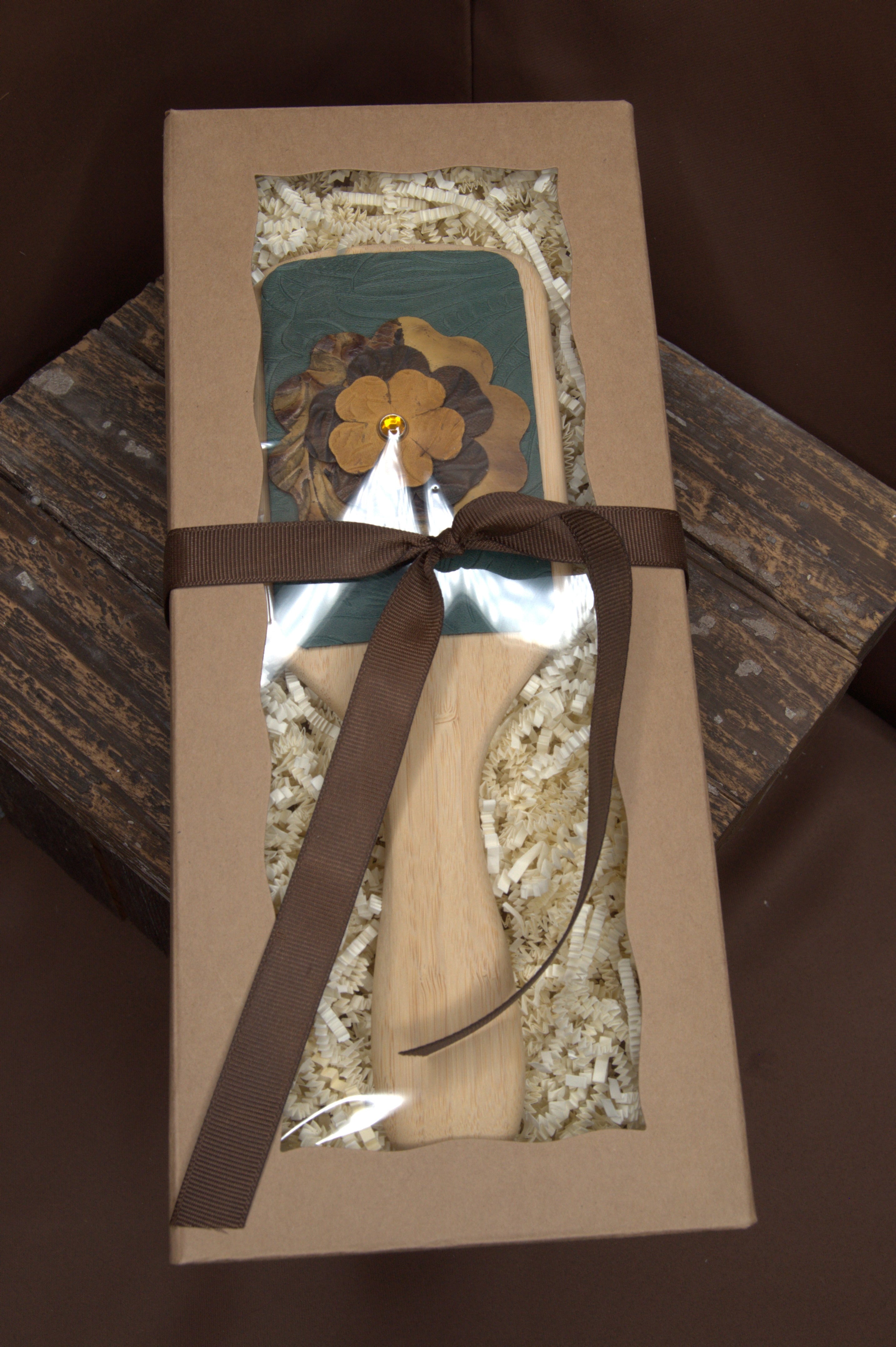 Leather accented hair brush in a decorative box with a brown ribbon on a wooden surface.