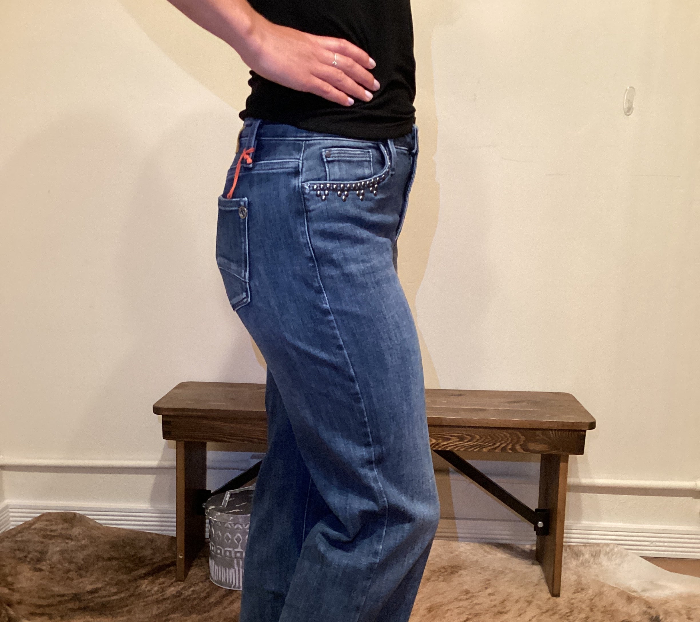 side view of Person wearing blue jeans with stud detailing on the edge of the front pockets