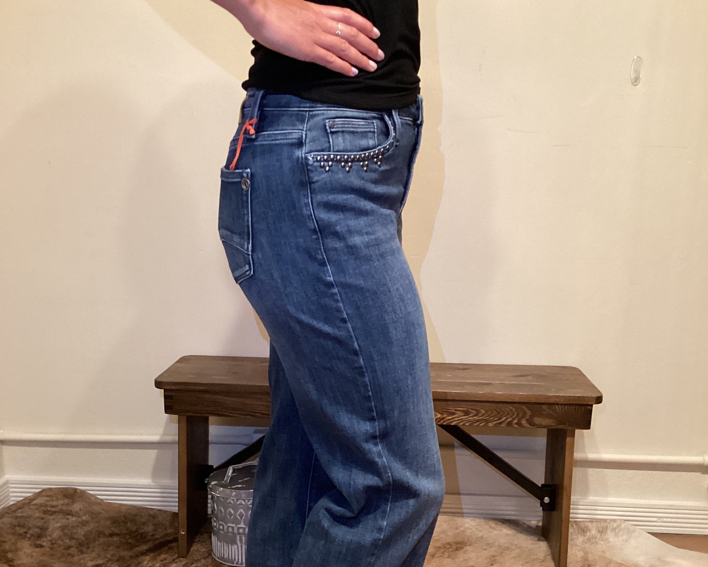 side view of Person wearing blue jeans with stud detailing on the edge of the front pockets