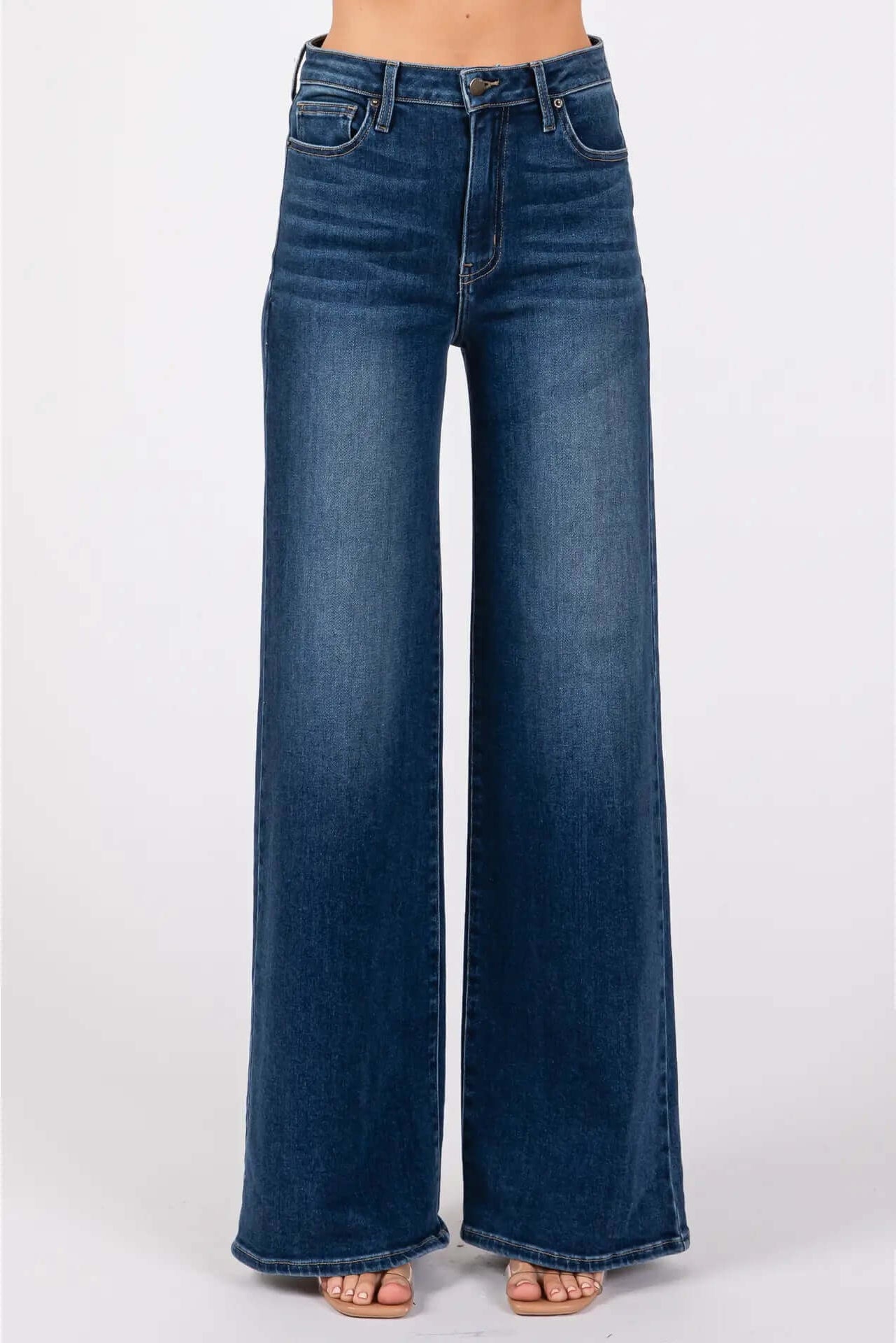 A pair of dark denim high-rise super wide leg jeans displayed on a model without showing the upper part of the body.