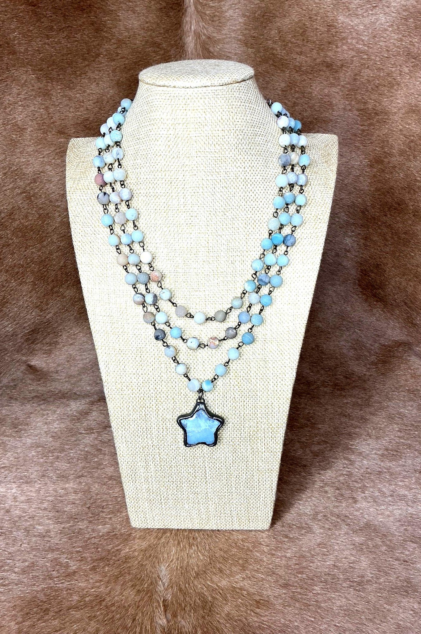 Necklace with a star-shaped pendant on a mannequin bust against a brown background