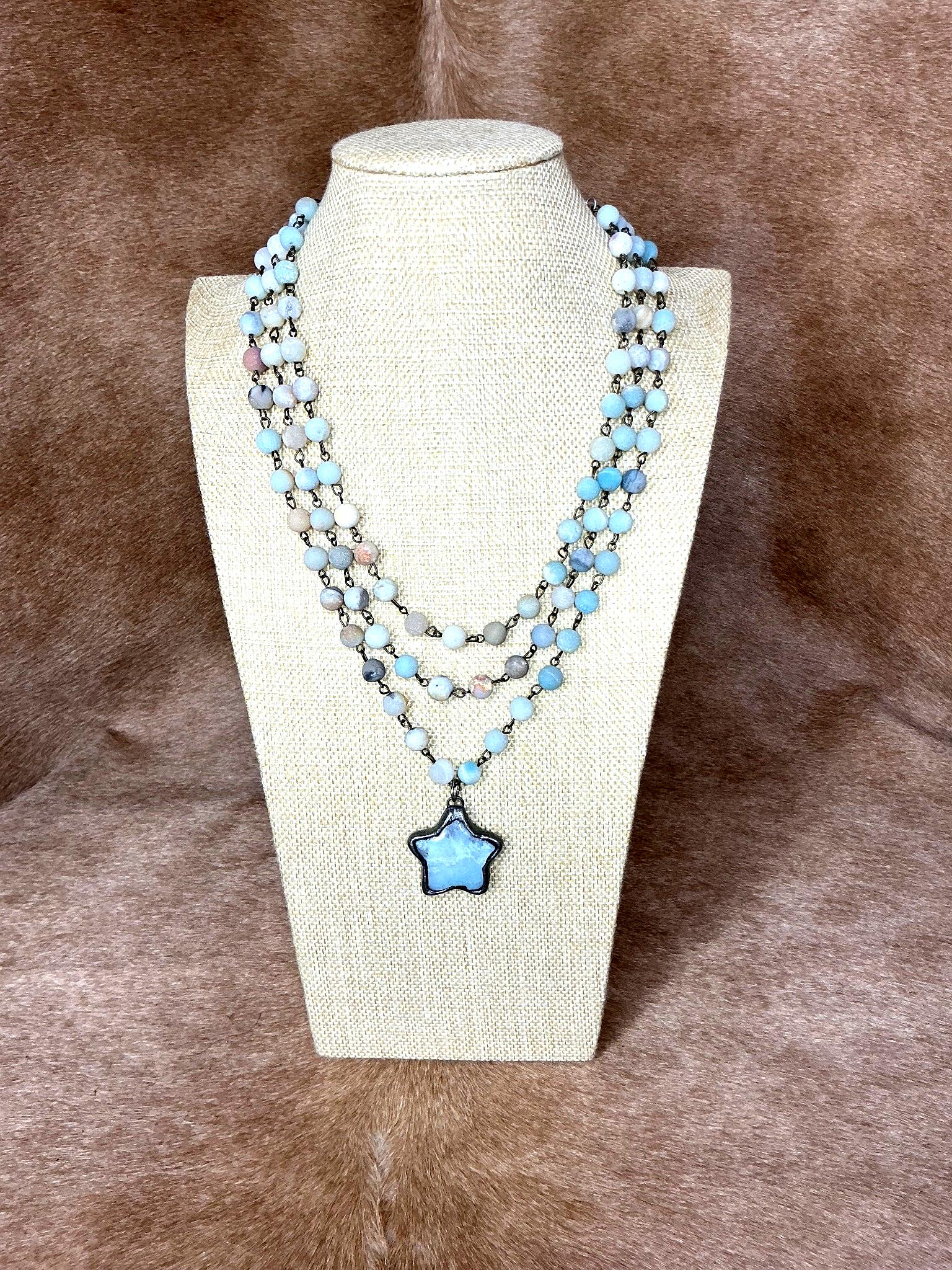 Necklace with a star-shaped pendant on a mannequin bust against a brown background