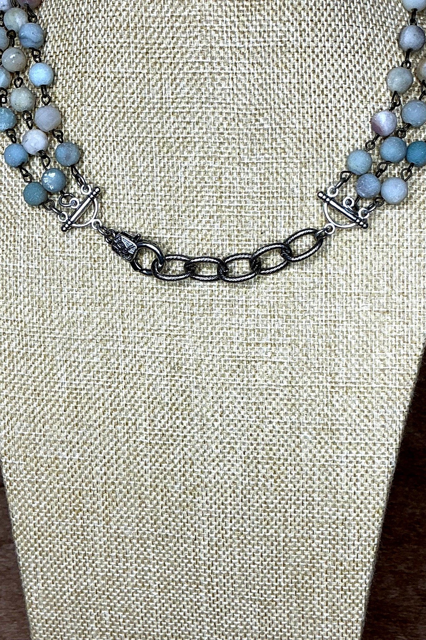 Necklace with blue beads and silver chain on a textured beige surface