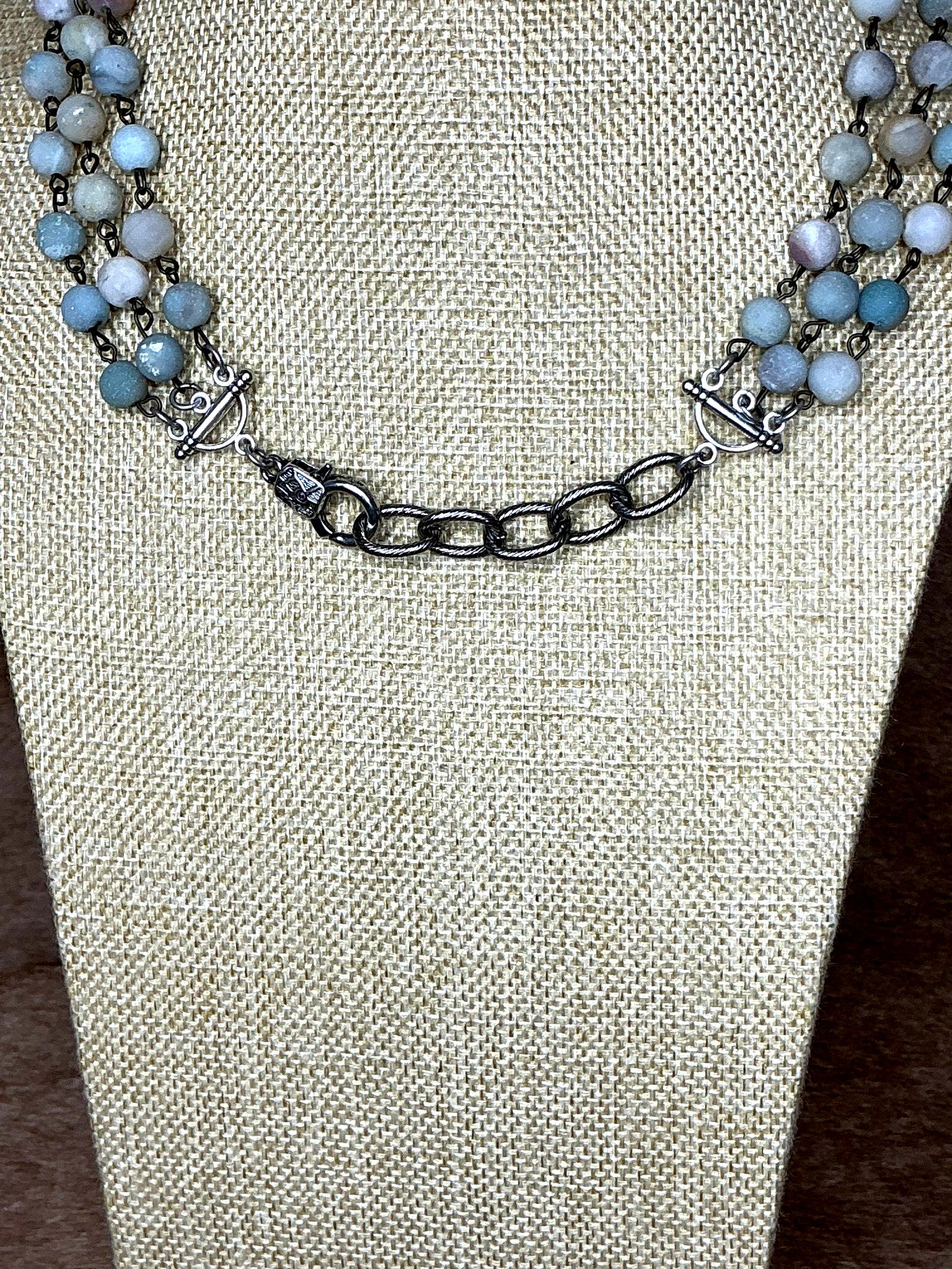 Necklace with blue beads and silver chain on a textured beige surface