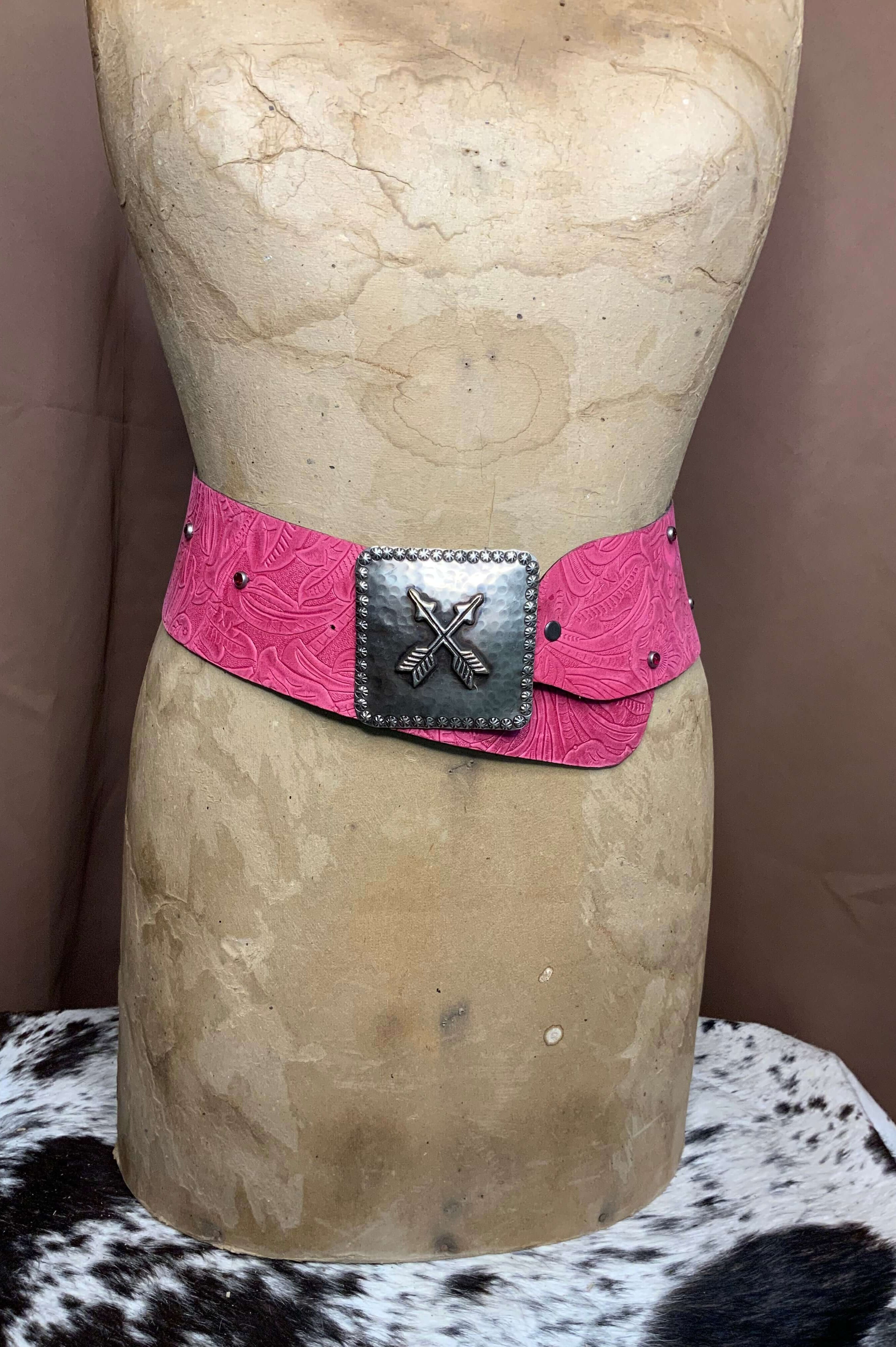 A pink embossed leather belt with a silver handcrafted buckle on display mannequin.