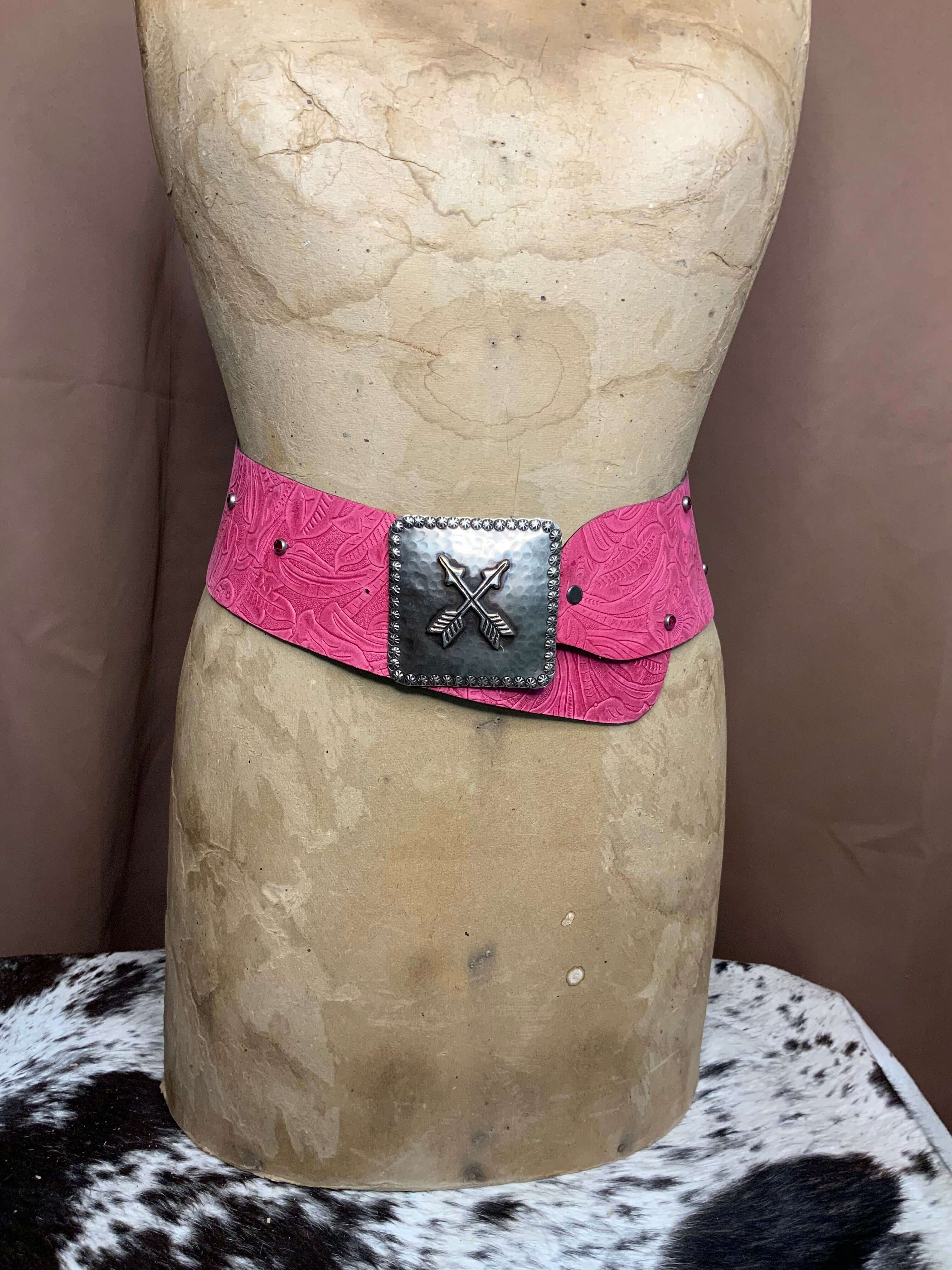 A pink embossed leather belt with a silver handcrafted buckle on display mannequin.