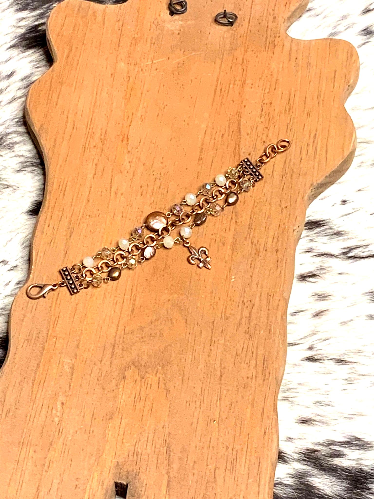 Handcrafted copper chain bracelet with mixed beads in warm neutral tones, featuring a fleur-de-lis charm