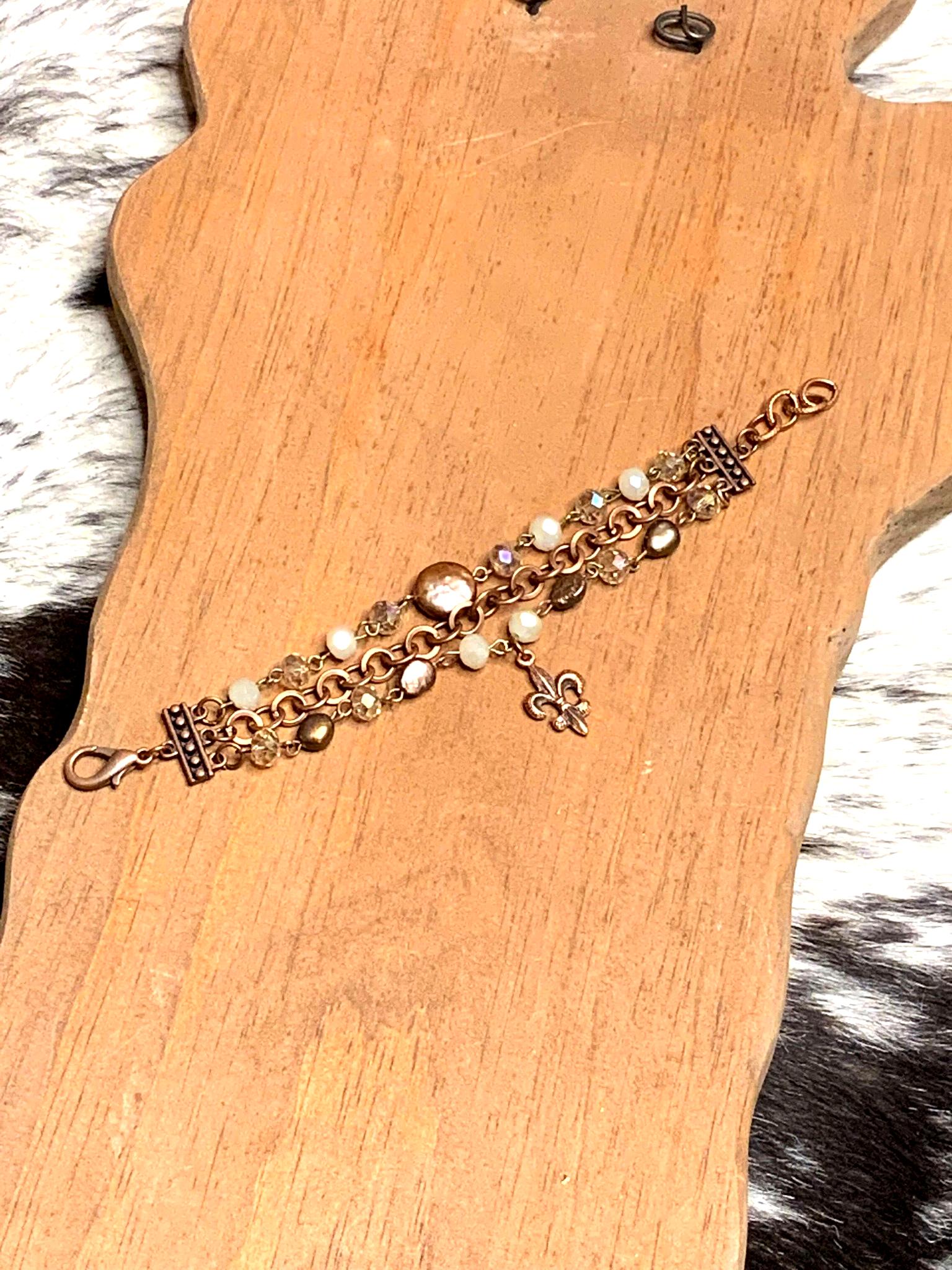 Detailed view of copper bracelet with round beads, crystal accents, and fleur-de-lis charm
