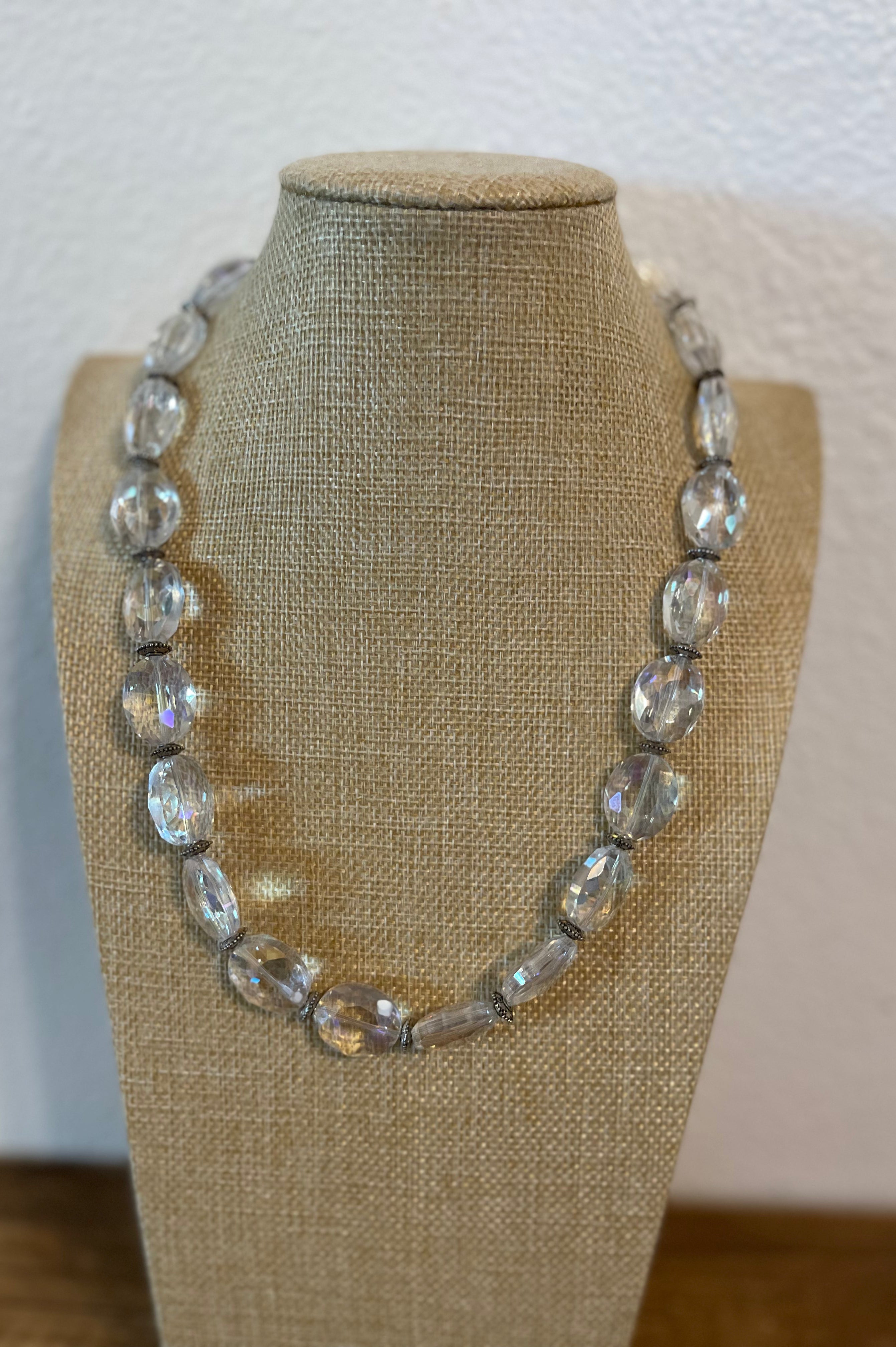 Necklace with clear beads on a mannequin bust against a plain background