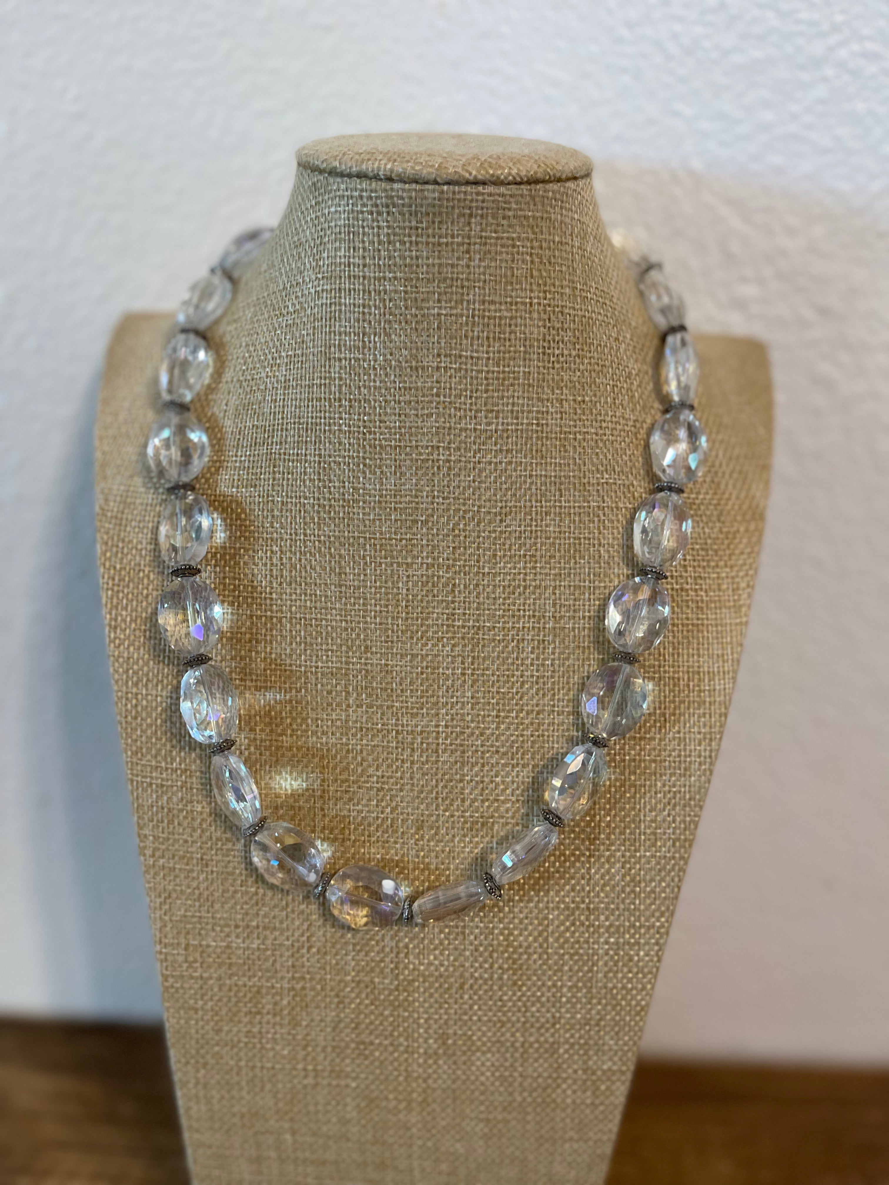 Necklace with clear beads on a mannequin bust against a plain background