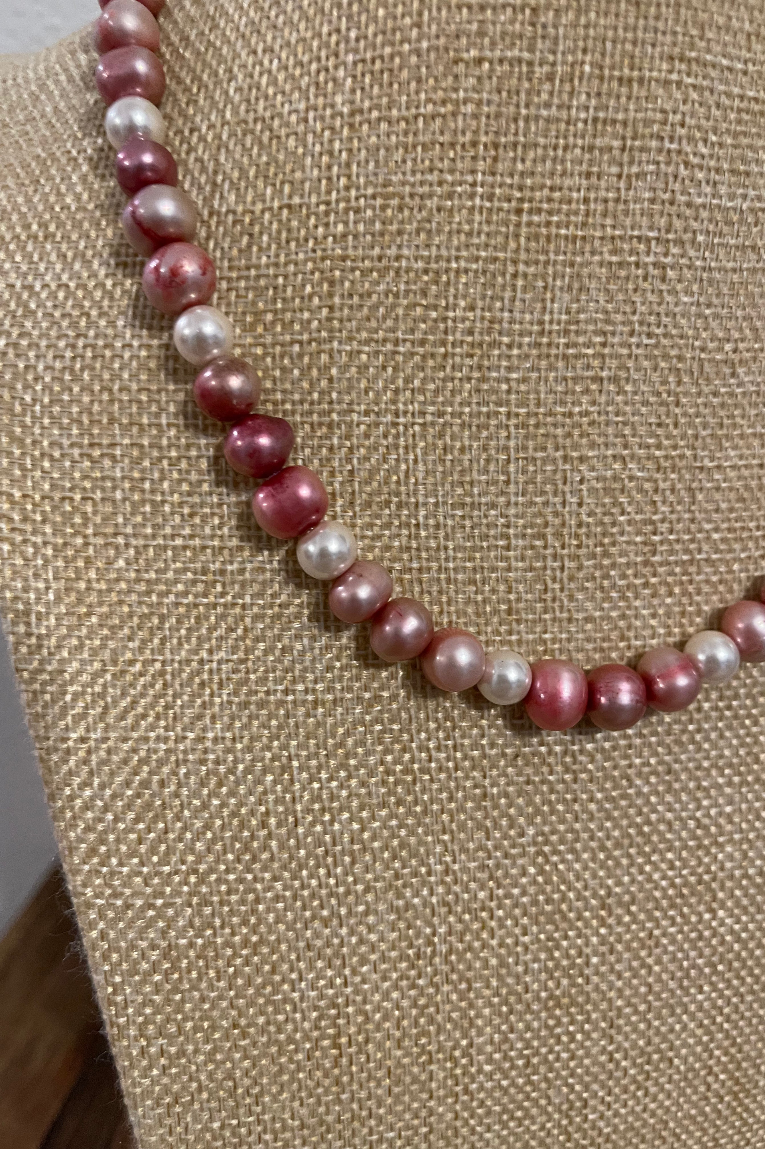 Necklace with pink and white pearls on a beige fabric background